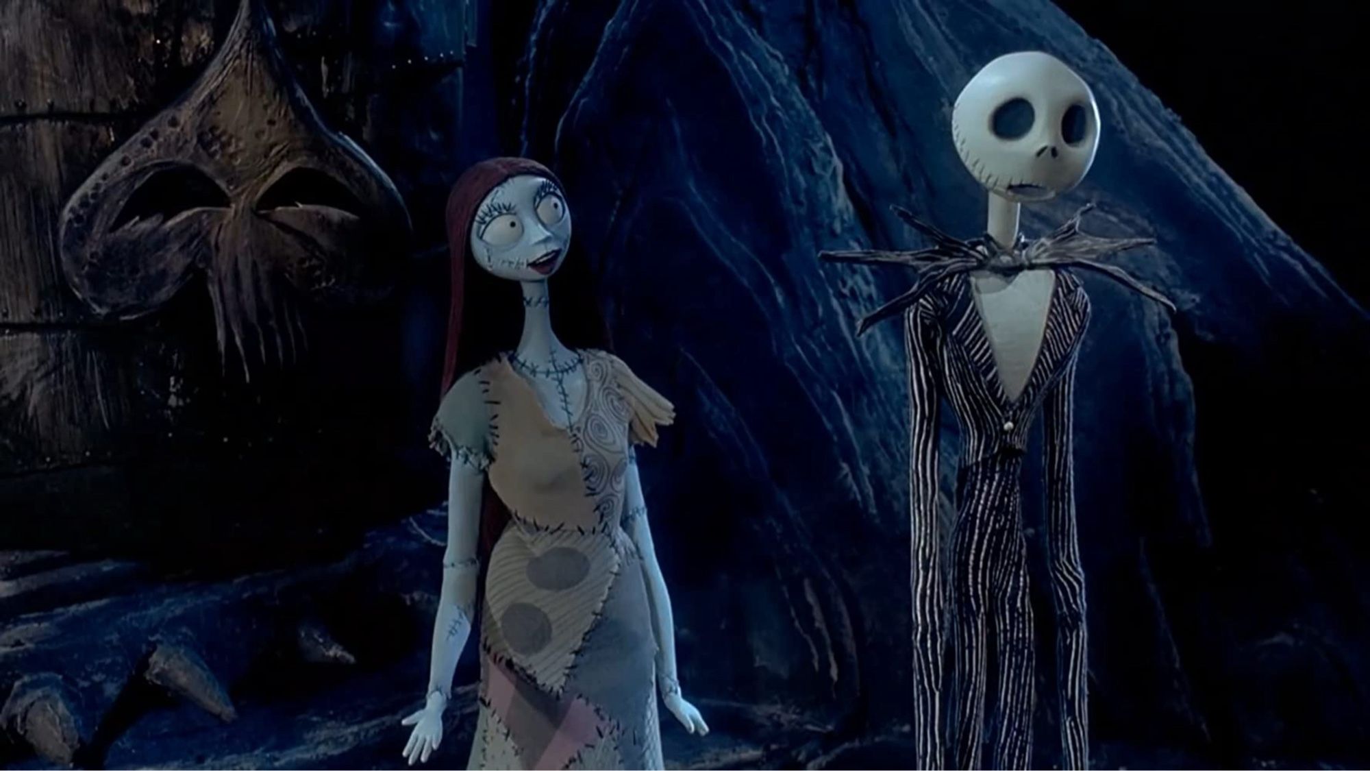 A patchwork woman and tall skeleton sing together in a forest.