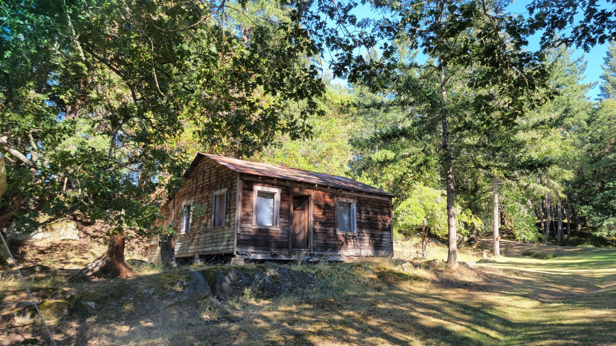 One of the Aquarian Foundation's wooden cabins, sitting in a treed area on a small mound