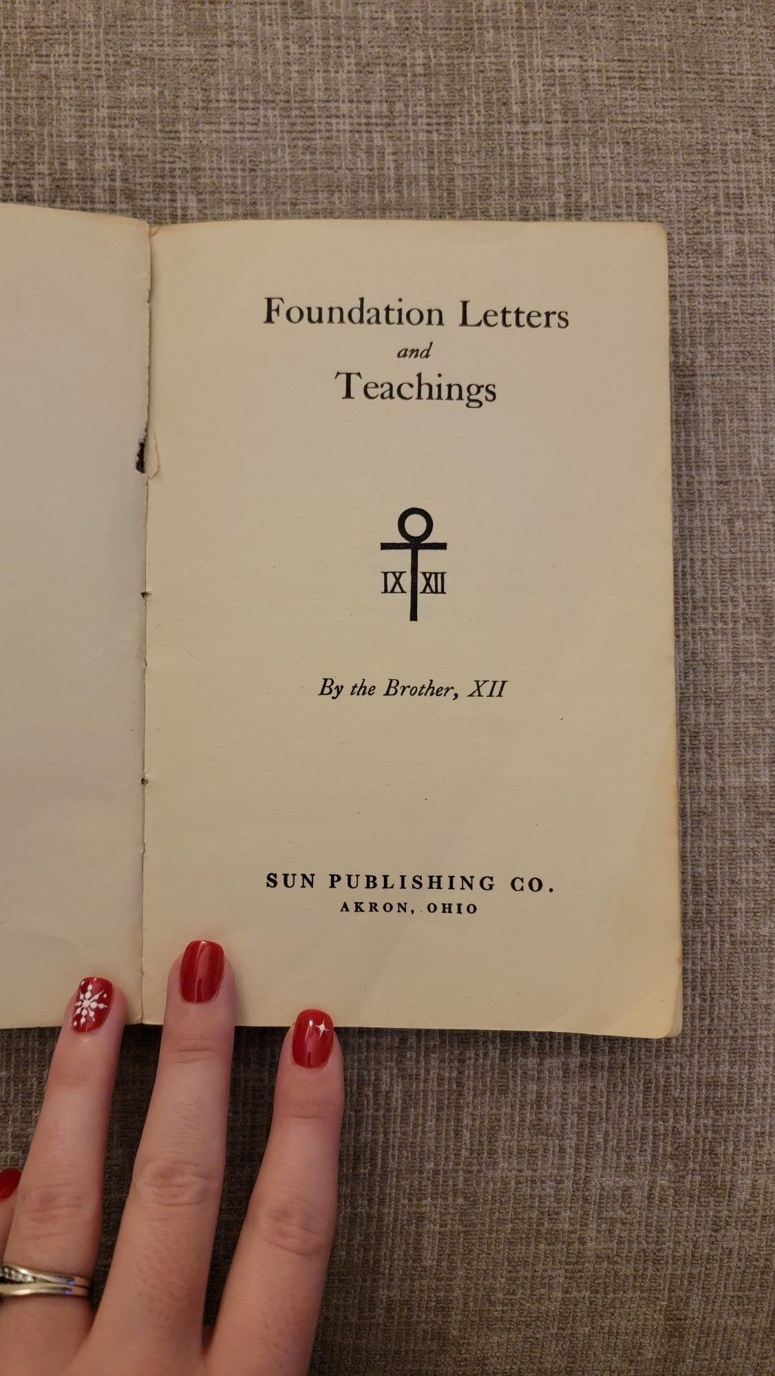 Inside title page repeating the book's title. It has an Egyptian tau symbol just below the title, with roman numerals 9 and 12 on either side of the tau. The author is the Brother, XII. And the book was published by the Sun Publishing Company in Akron, Ohio, in 1927.