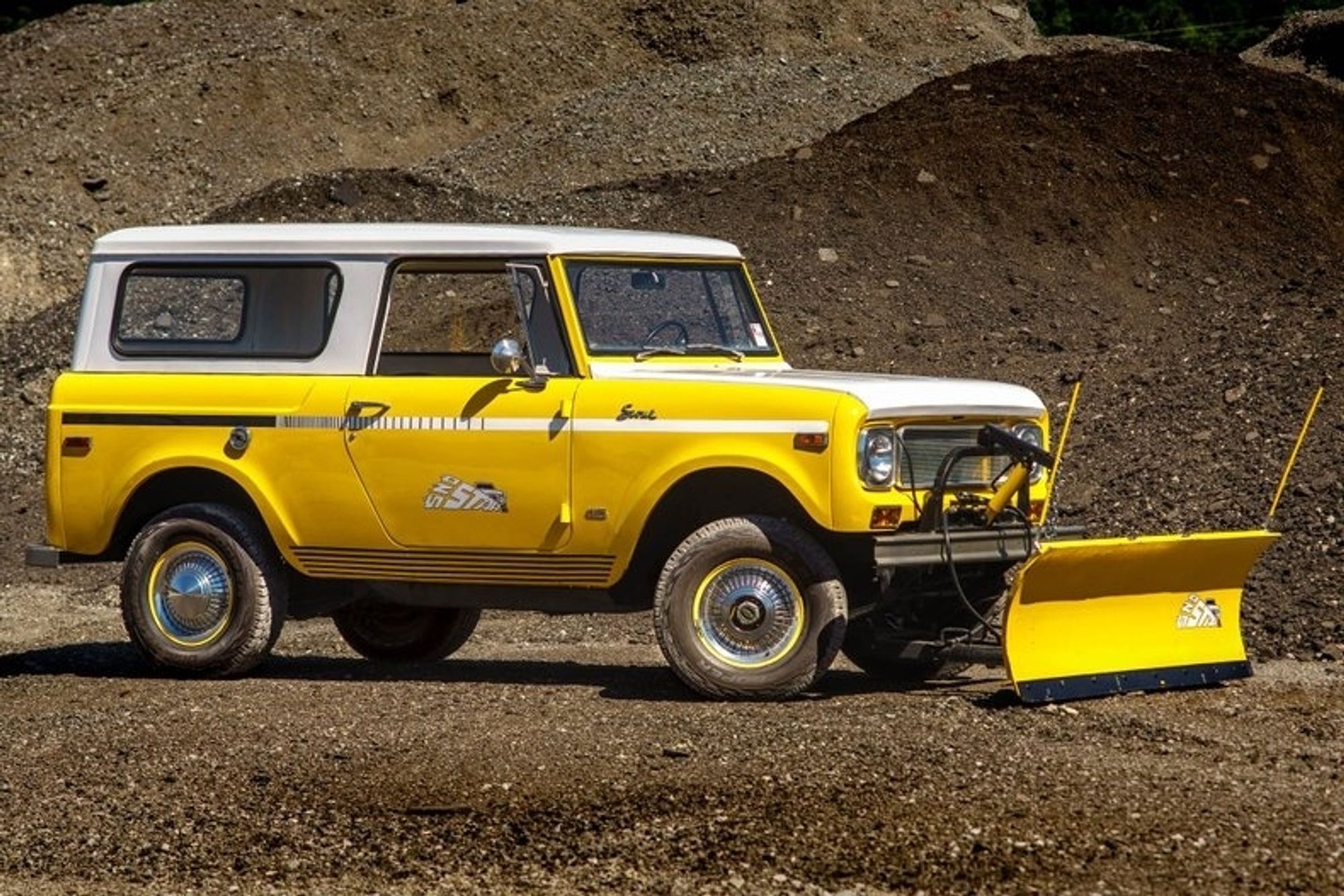 A bright yellow International Scout, a truck made from the 1960s to the 1980s. An open top pickup with a optional camper shell, it's the precursor to the Bronco and modern SUVs.

This one has a snow plow attachment to the front bumper. Something that, with Tim Walz living in a northern state, I wouldn't be surprised if he owned for his Scout