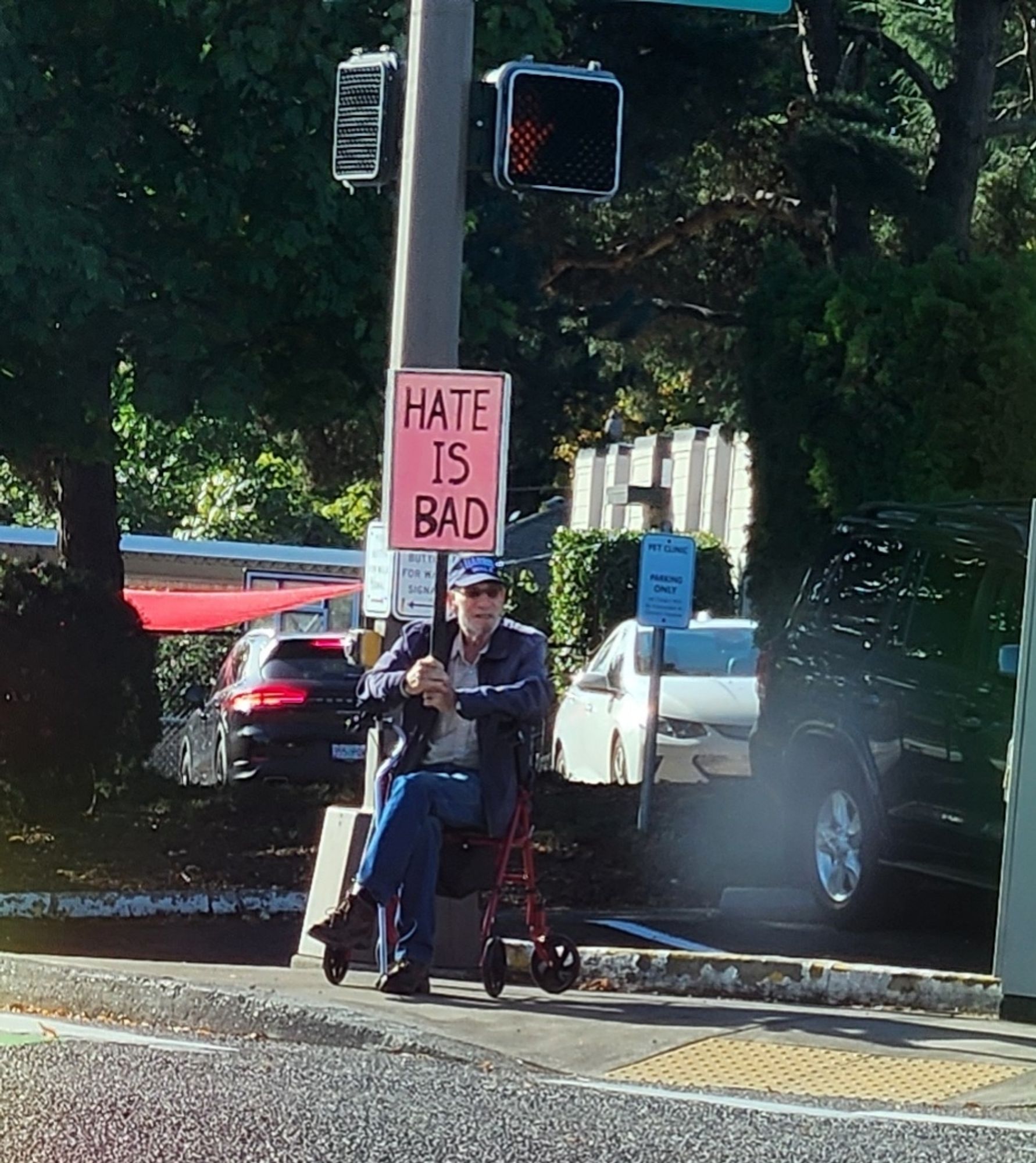 Old man holding sign saying Hate is Bad