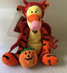 A plushie of Tigger (from Winnie the Pooh) dressed up as a devil for Halloween, complete with horns, a cape, a pitchfork, and a jack-o-lantern shaped candy basket.