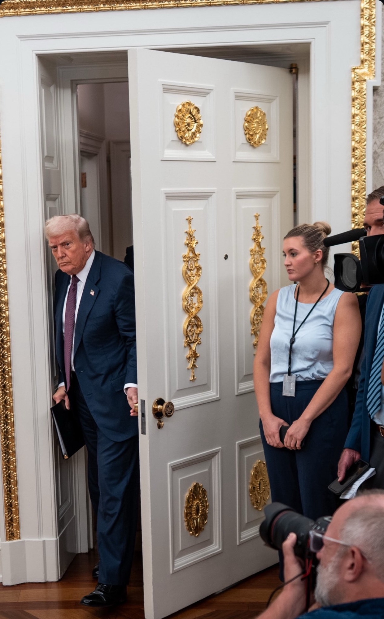 Trump opening a door and I believe the oval office that has been slathered with tacky gold embellishments. 