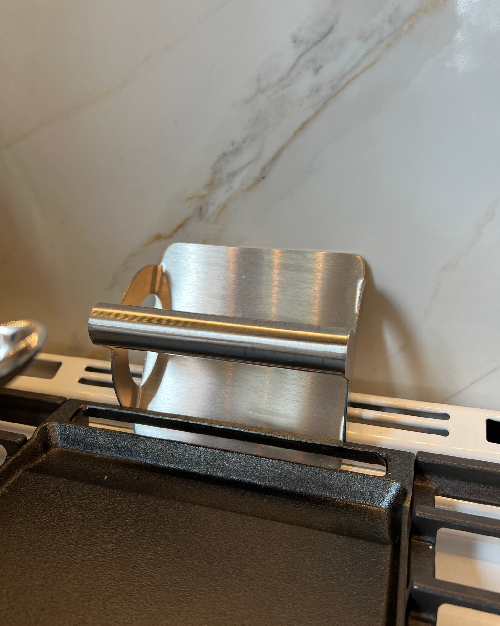A stainless steel hamburger smasher resting on my stove