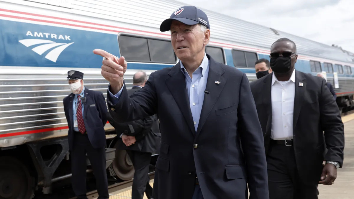 Joe Biden, a former vice president known for taking the train all the time, standing in front of a Amtrak train car
