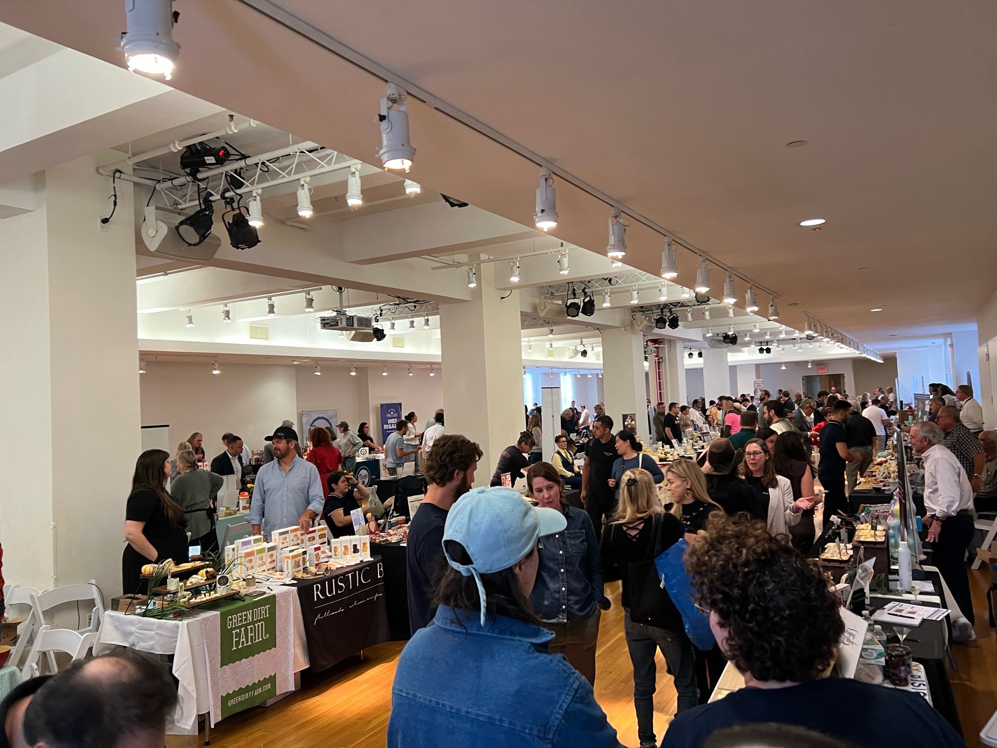 Big room full of cheese producers offering samples