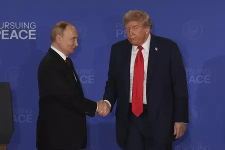 Photo of Putin, looking smug and extremely self satisfied, shaking hands with Trump, who looks like maybe he died three days ago. 