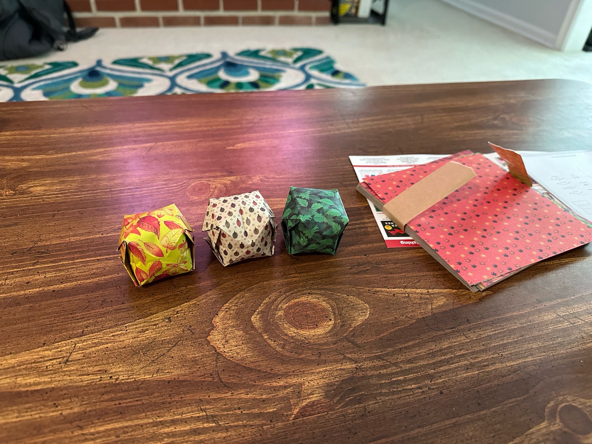 An image of three small origami balloons and some origami paper sheets