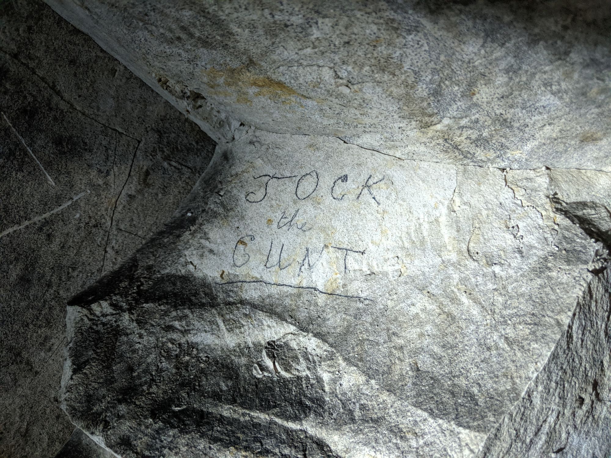 Trench tunnel wall with "Jock the Cunt" scrawled on it. Cunt is underlined.