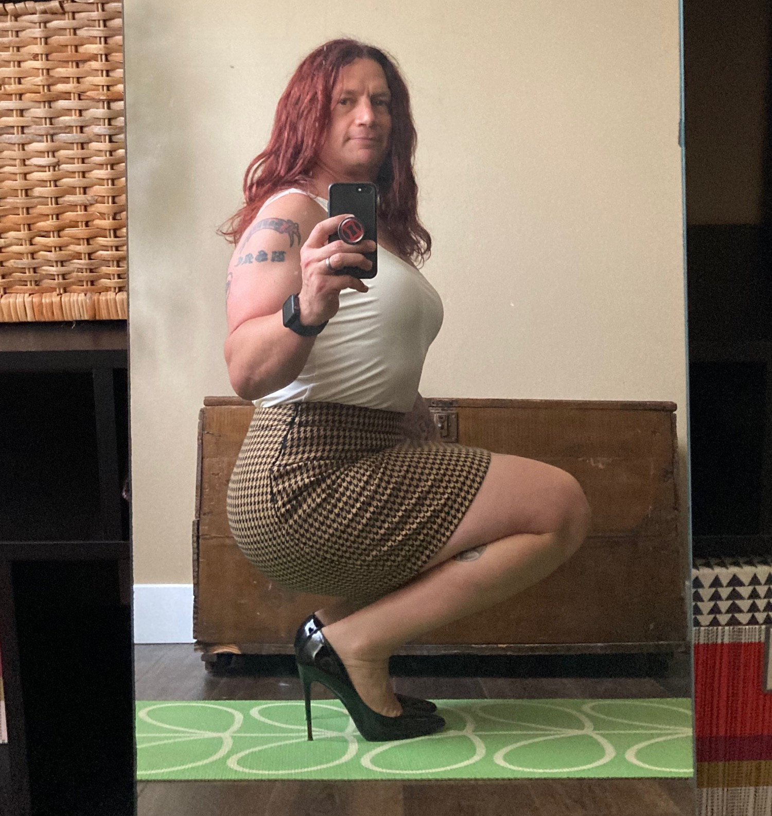 Lauren in another mirror selfie. This is a profile in the light brown skirt, white cami, and black heels. No blazer.