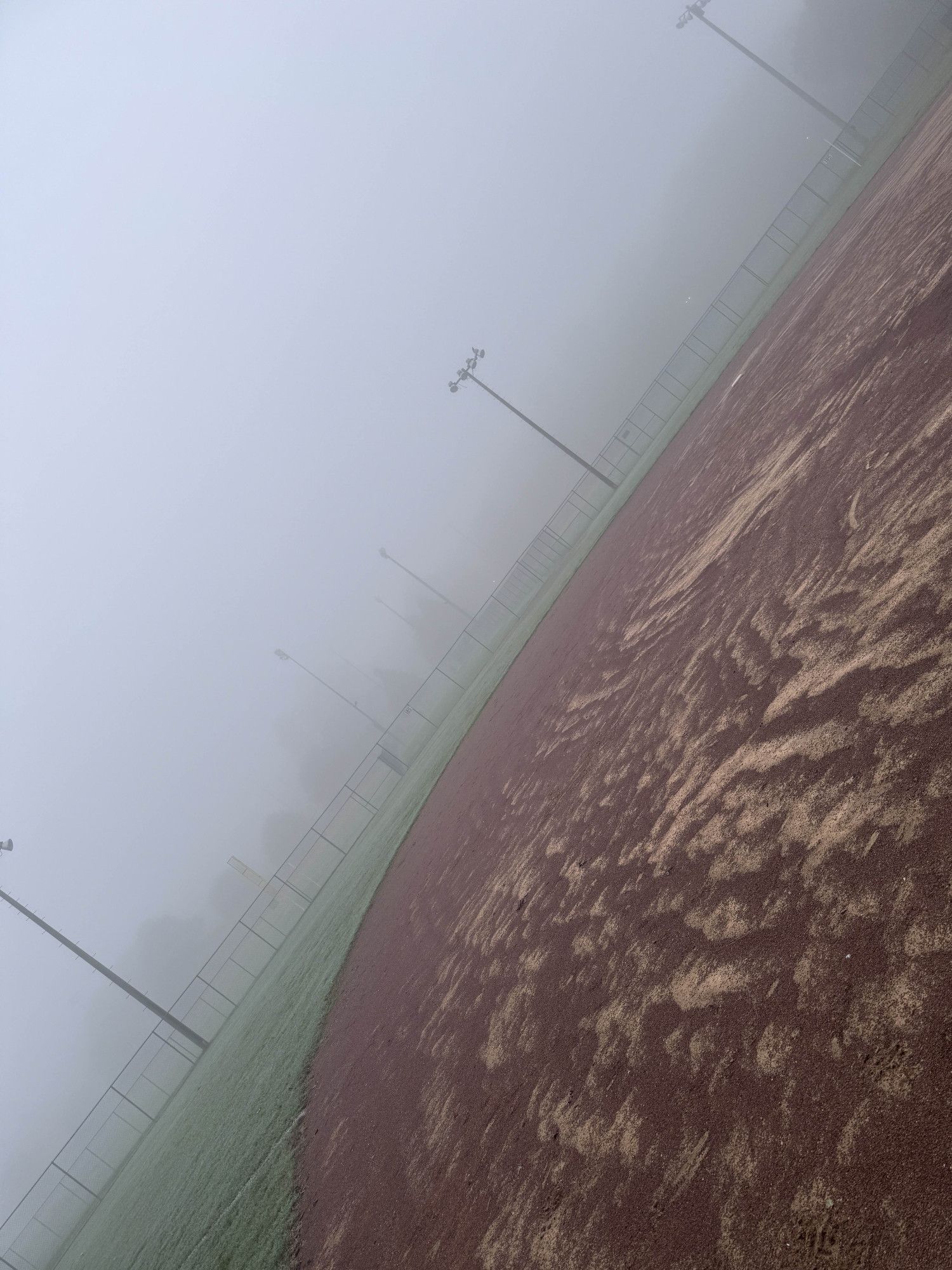 A foggy baseball field photographed at a steep angle.