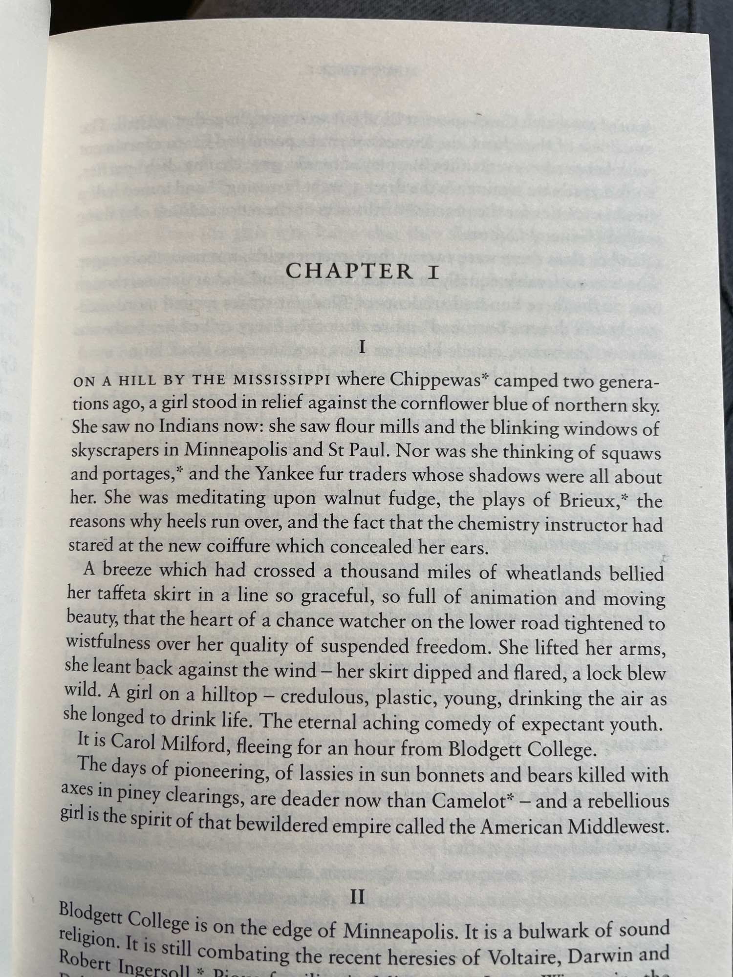 CHAPTER I
I
ON A HILL BY THE MISSISSIPPI Where Chippewas* camped two generations ago, a girl stood in relief against the cornflower blue of northern sky.
She saw no Indians now: she saw flour mills and the blinking windows of skyscrapers in Minneapolis and St Paul. Nor was she thinking of squaws and portages," and the Yankee fur traders whose shadows were all about her. She was meditating upon walnut fudge, the plays of Brieux," the reasons why heels run over, and the fact that the chemistry instructor had stared at the new coiffure which concealed her ears.
A breeze which had crossed a thousand miles of wheatlands bellied her taffeta skirt in a line so graceful, so full of animation and moving beauty, that the heart of a chance watcher on the lower road tightened to wistfulness over her quality of suspended freedom. She lifted her arms, she leant back against the wind - her skirt dipped and flared, a lock blew wild. A girl on a hilltop - credulous, plastic, young, drinking the air as she longed to drink life. The eternal aching comedy of expectant youth.
It is Carol Milford, fleeing for an hour from Blodgett College.
The days of pioneering, of lassies in sun bonnets and bears killed with axes in piney clearings, are deader now than Camelot* - and a rebellious girl is the spirit of that bewildered empire called the American Middlewest.