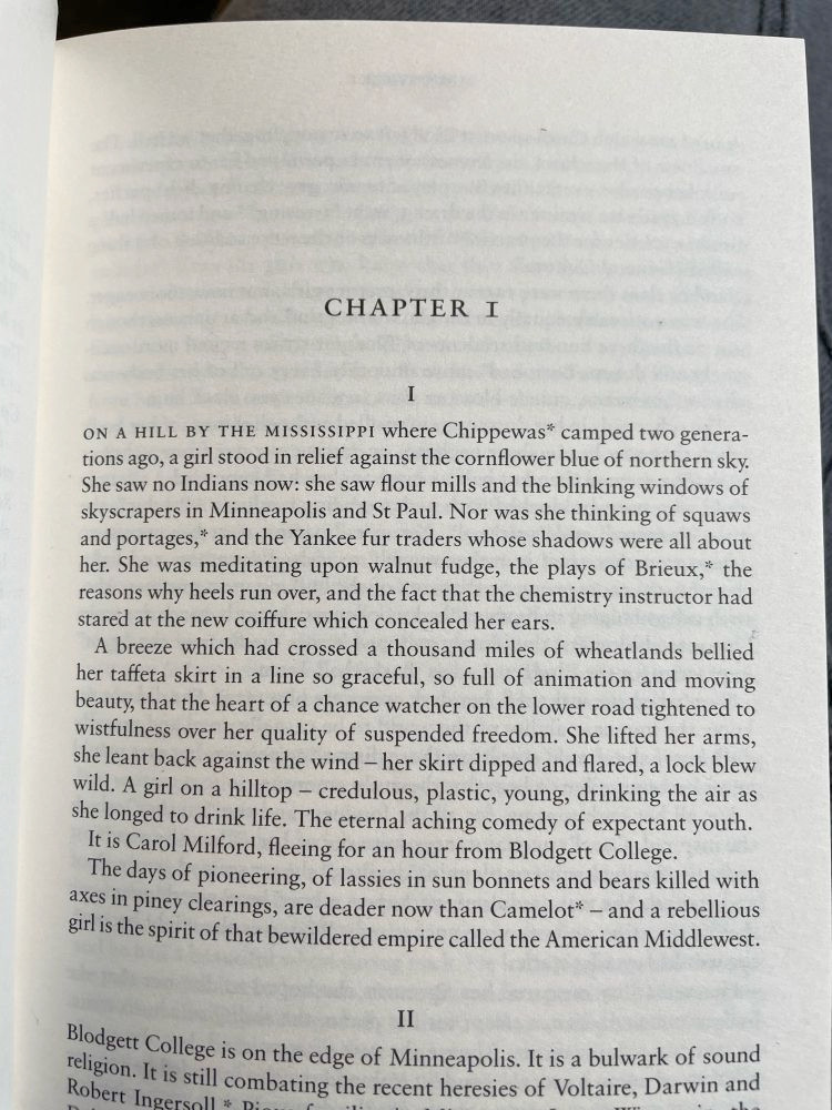 CHAPTER I
I
ON A HILL BY THE MISSISSIPPI Where Chippewas* camped two generations ago, a girl stood in relief against the cornflower blue of northern sky.
She saw no Indians now: she saw flour mills and the blinking windows of skyscrapers in Minneapolis and St Paul. Nor was she thinking of squaws and portages," and the Yankee fur traders whose shadows were all about her. She was meditating upon walnut fudge, the plays of Brieux," the reasons why heels run over, and the fact that the chemistry instructor had stared at the new coiffure which concealed her ears.
A breeze which had crossed a thousand miles of wheatlands bellied her taffeta skirt in a line so graceful, so full of animation and moving beauty, that the heart of a chance watcher on the lower road tightened to wistfulness over her quality of suspended freedom. She lifted her arms, she leant back against the wind - her skirt dipped and flared, a lock blew wild. A girl on a hilltop - credulous, plastic, young, drinking the air as she longed to drink life. The eternal aching comedy of expectant youth.
It is Carol Milford, fleeing for an hour from Blodgett College.
The days of pioneering, of lassies in sun bonnets and bears killed with axes in piney clearings, are deader now than Camelot* - and a rebellious girl is the spirit of that bewildered empire called the American Middlewest.