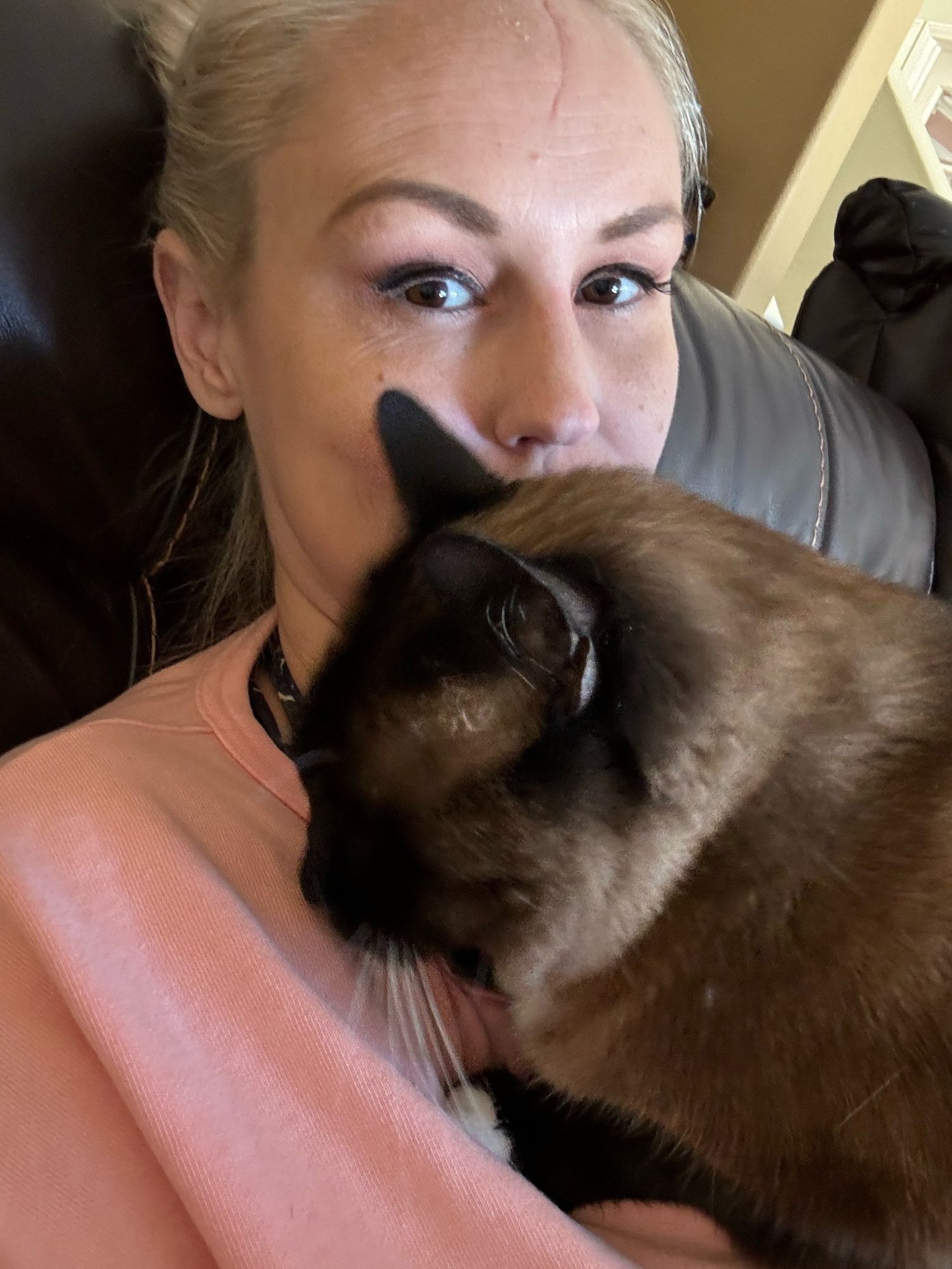 Girl with a Siamese cat on her chest 