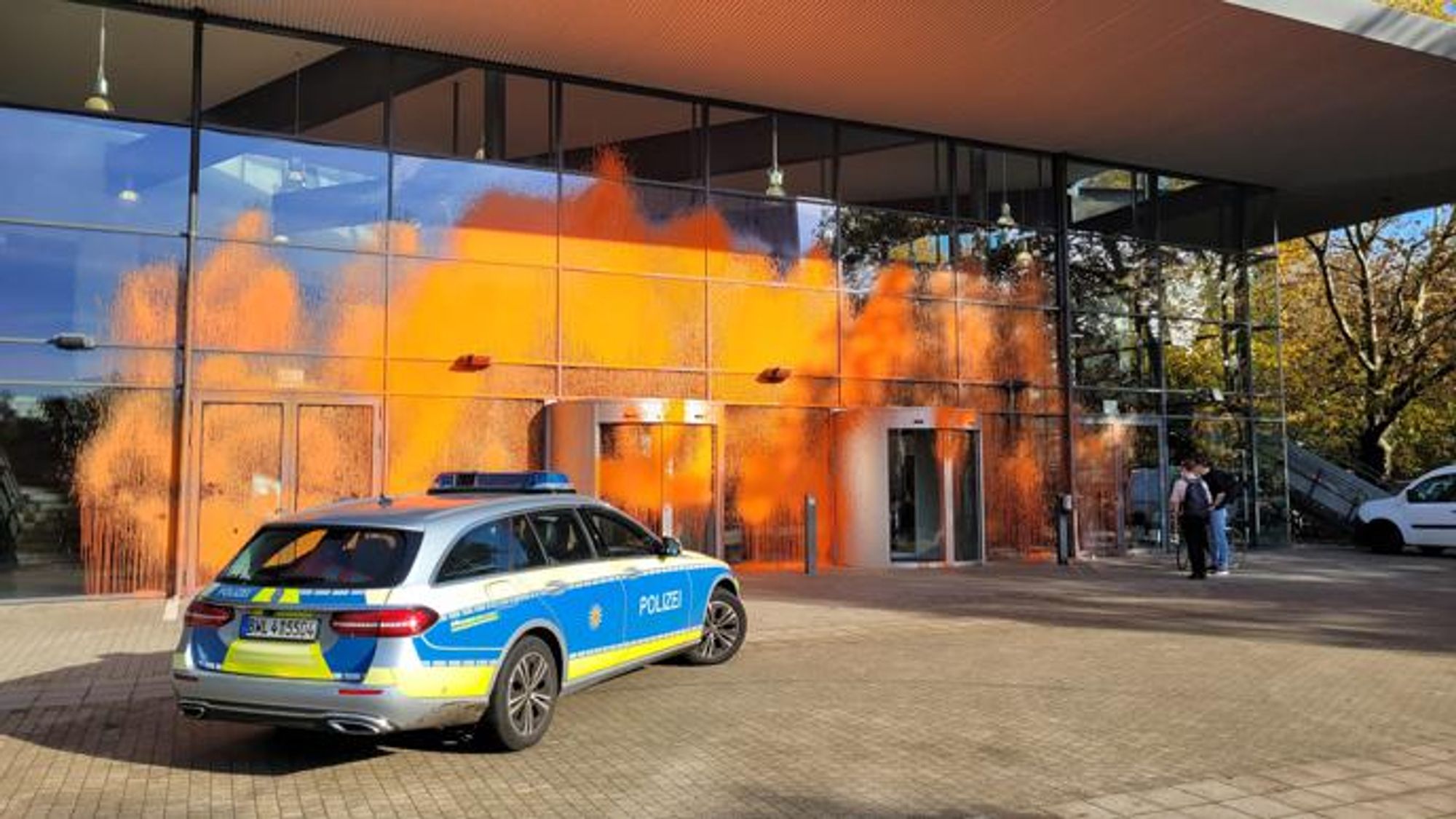 Die Glasscheiben des Audimax am KIT waren von den Aktivistinnen mit Farbe besprüht worden. Ein Polizeiauto steht vor dem Hörsaal kurz nach der Aktion.