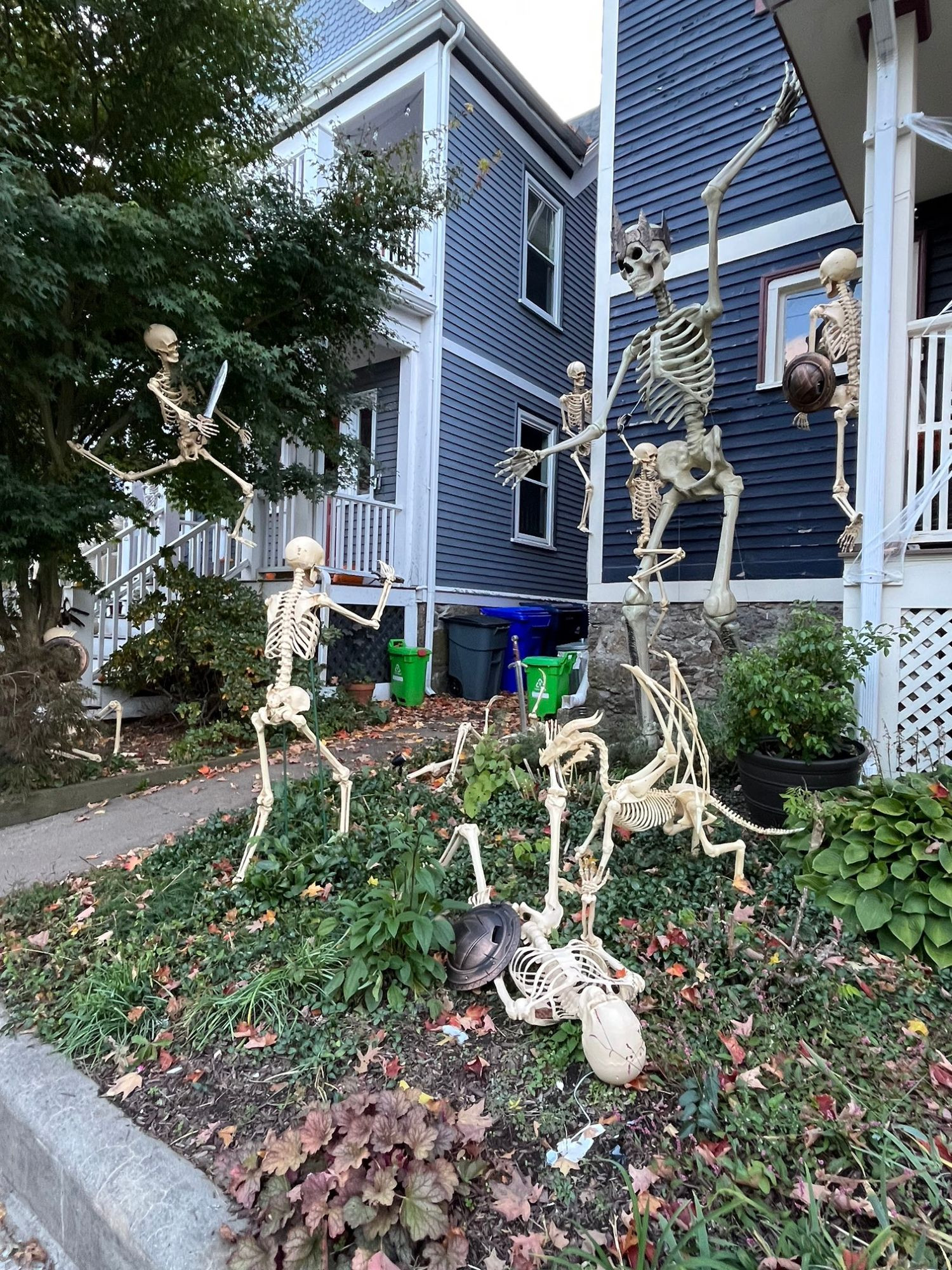 frontyard with a giant king skeleton and about 6 smaller skeletons posed in an epic battle, including a dragon skeleton
