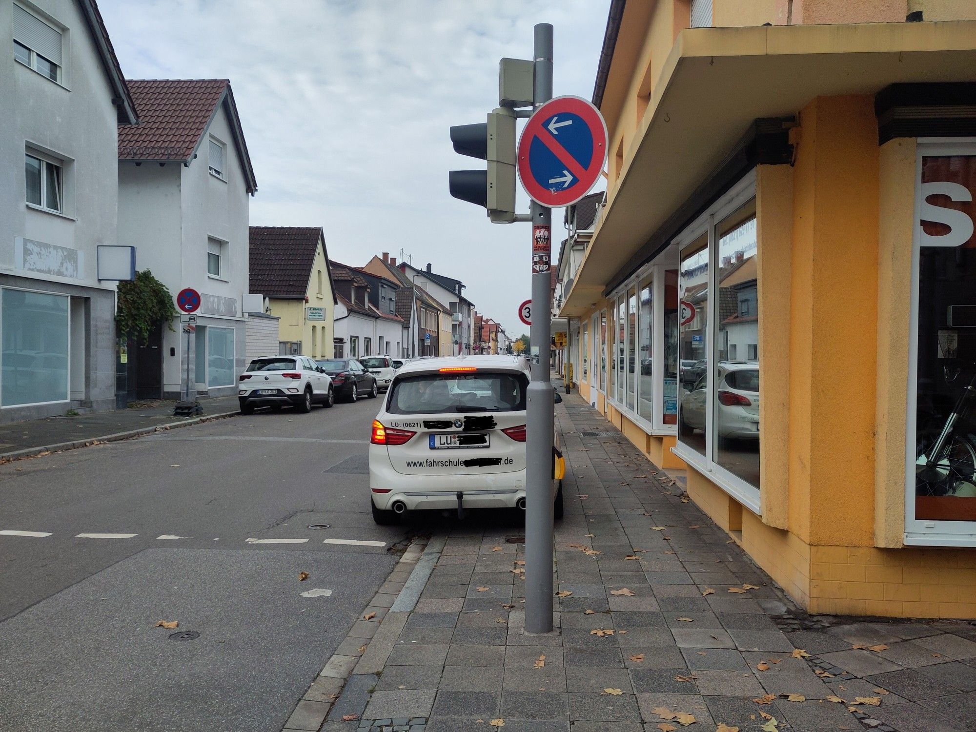 Fahrschul-Auto parkt mit eingeschaltetem Warnblinker auf dem Gehweg im (eingeschränkten) Parkverbot an einem Fußgängerüberweg (mit Ampel)