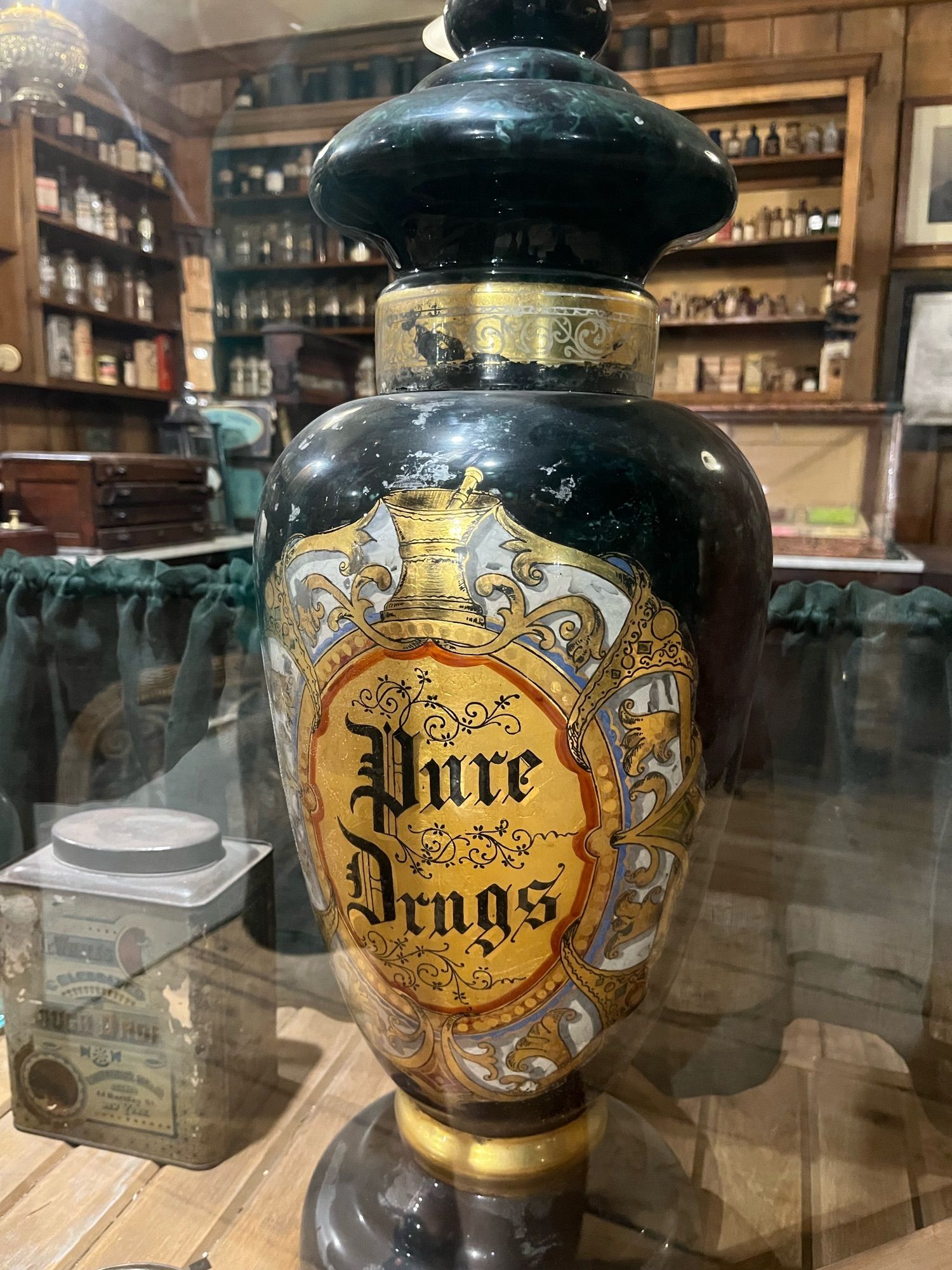 An old urn looking thing that very elaborately has “pure drugs” painted on it.