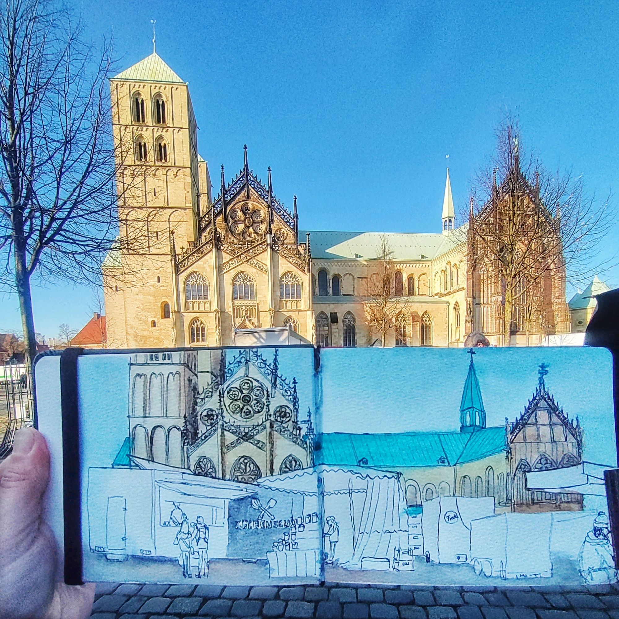 Sketchbook with motive painted held up in front of cathedral and market