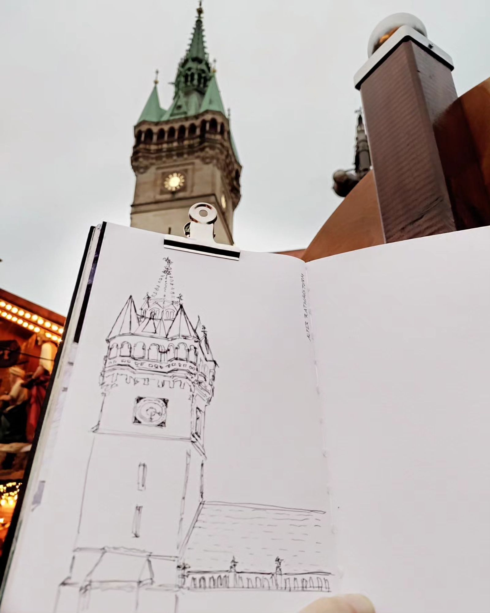 Sketchbook with b/w sketch of townhall tower that's visible behind it