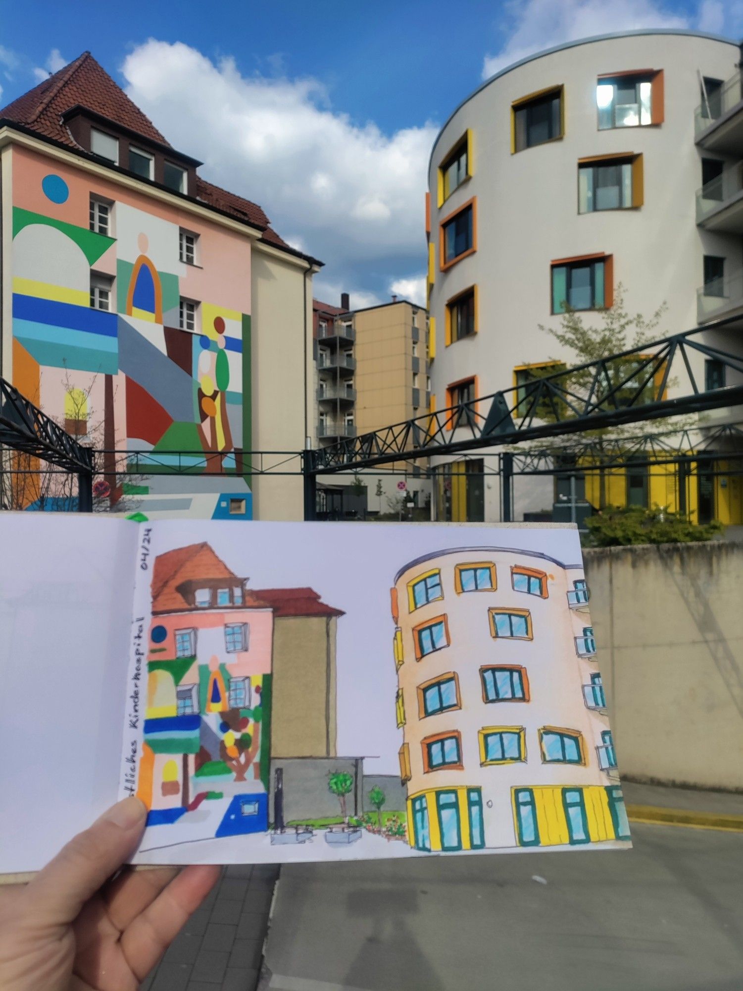 Urban sketch with markers of colorful buildings of a childrens hospital, held in front of the real buildings