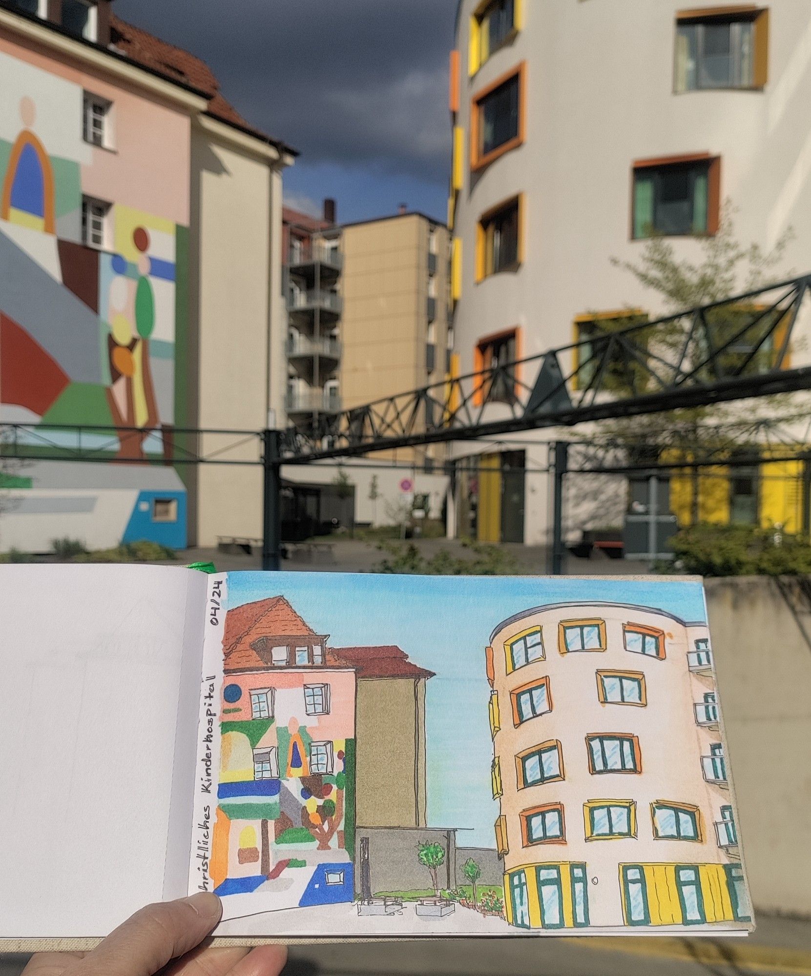 Urban sketch with markers of colorful buildings of a childrens hospital, held in front of the real buildings