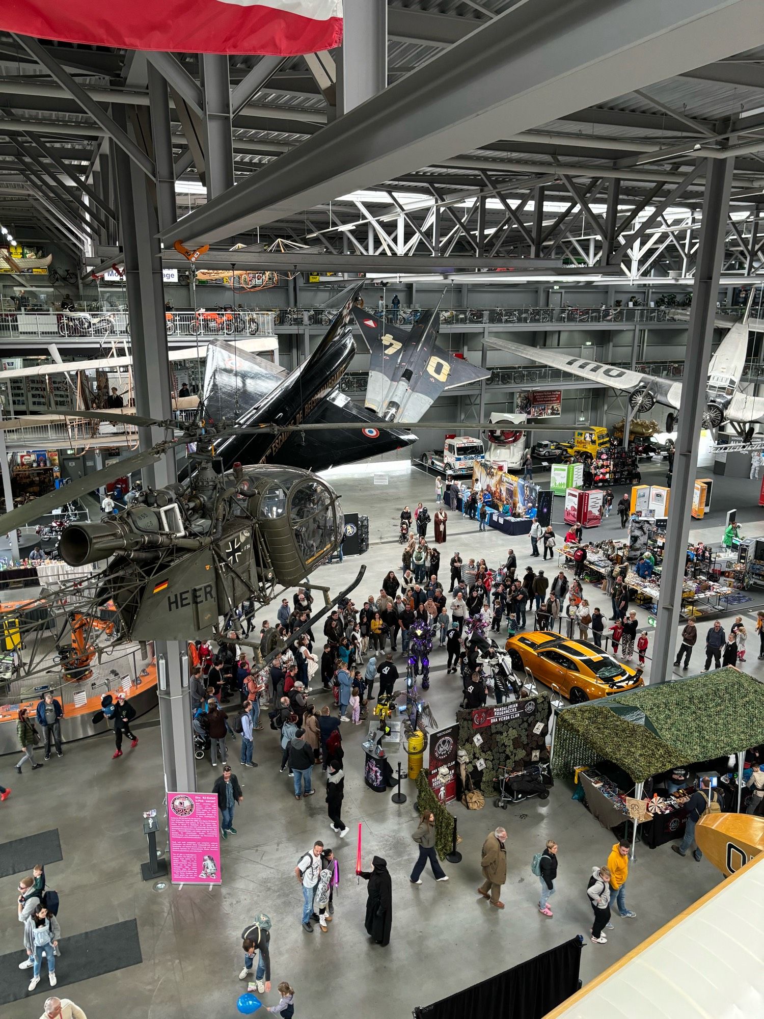 Foto aus Vogelperspektive in die Raumfahrthalle mit zahlreichen tollen Ausstellungsstücken und darunter den Ständen der SF-Aussteller.