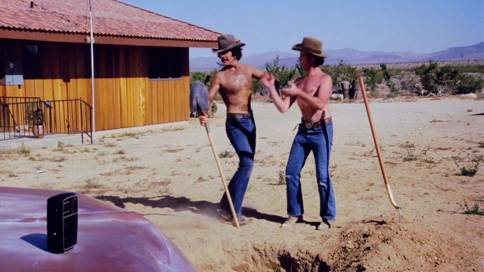 FIlm cap of our two heroes, the GOOD TIME OUTLAWS (I guess) hard at work just before they get fired ("You can't fire us, we quit!") They are both shirtless but with cowboy hats for the sake of decency and dancing outside with some shovels. One of 'em is using a shovel as a partner for a jig or whatever, while the other one claps in time. They really do have good times.