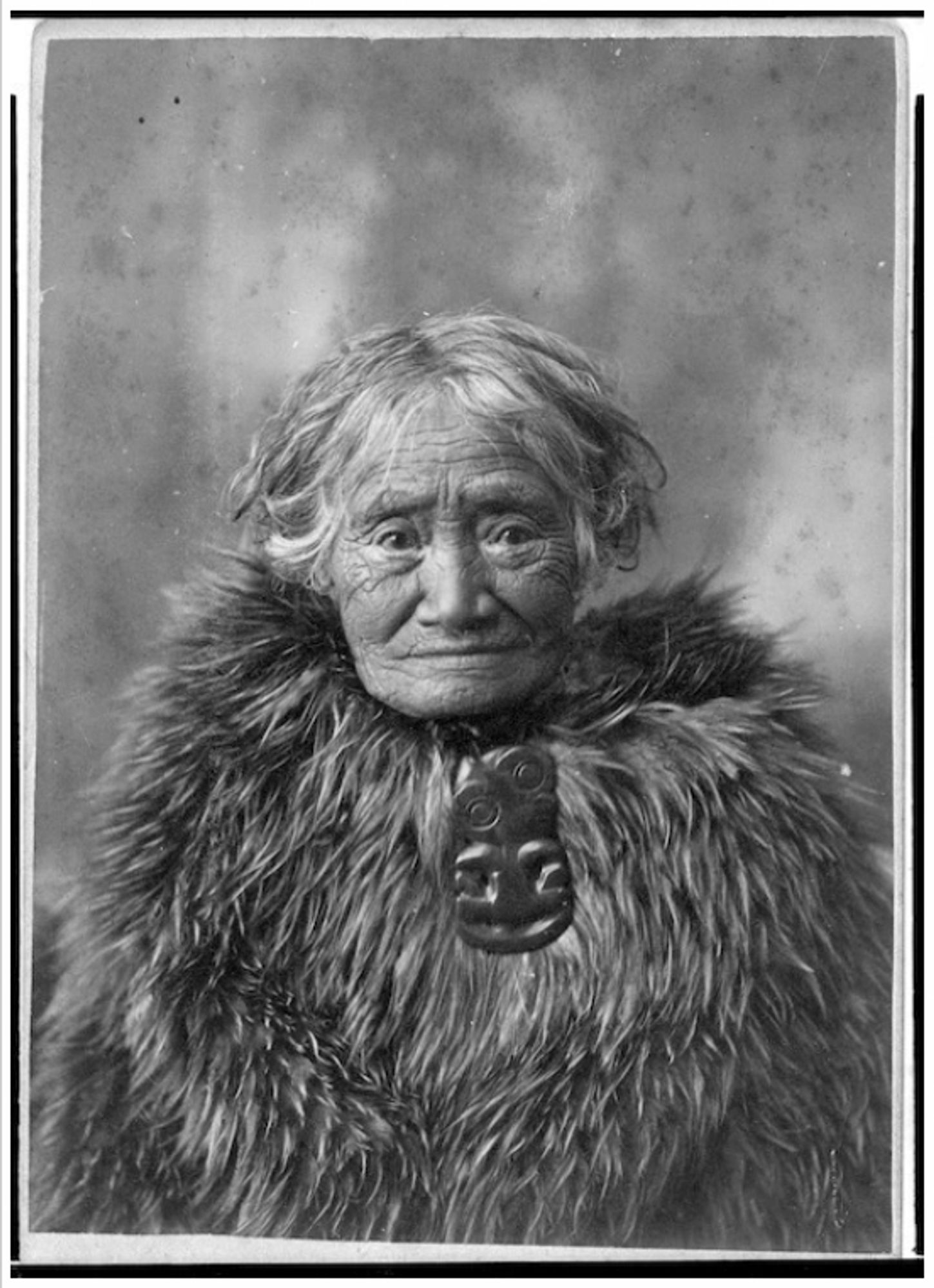 Merenako of Motueka, also known as Old Biddy, as an old woman wearing a kahukiwi (Māori kiwi feather cloak) and hei tiki.