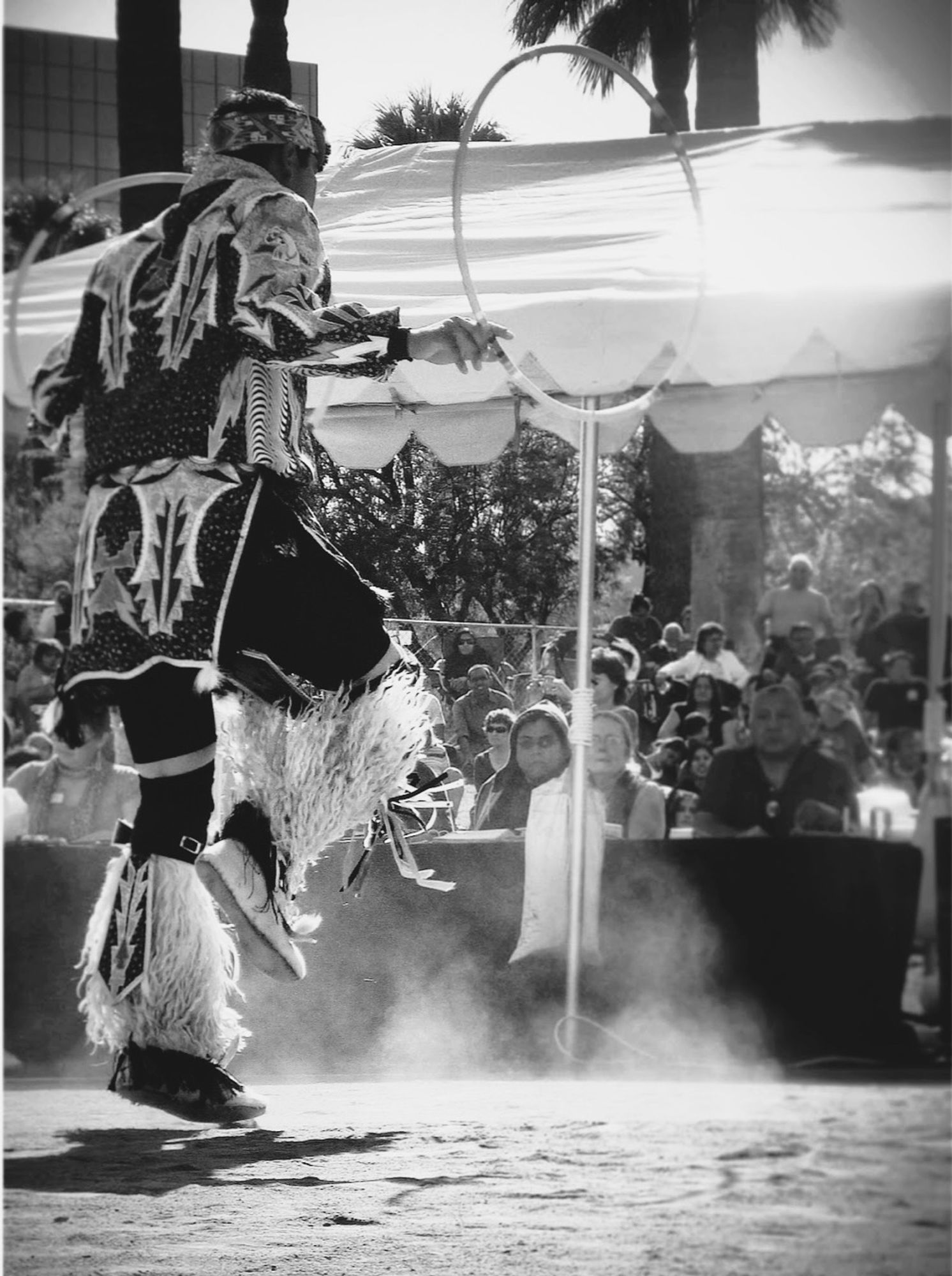 Black and White photo of a Hoop Dancer performing while a crowd watches