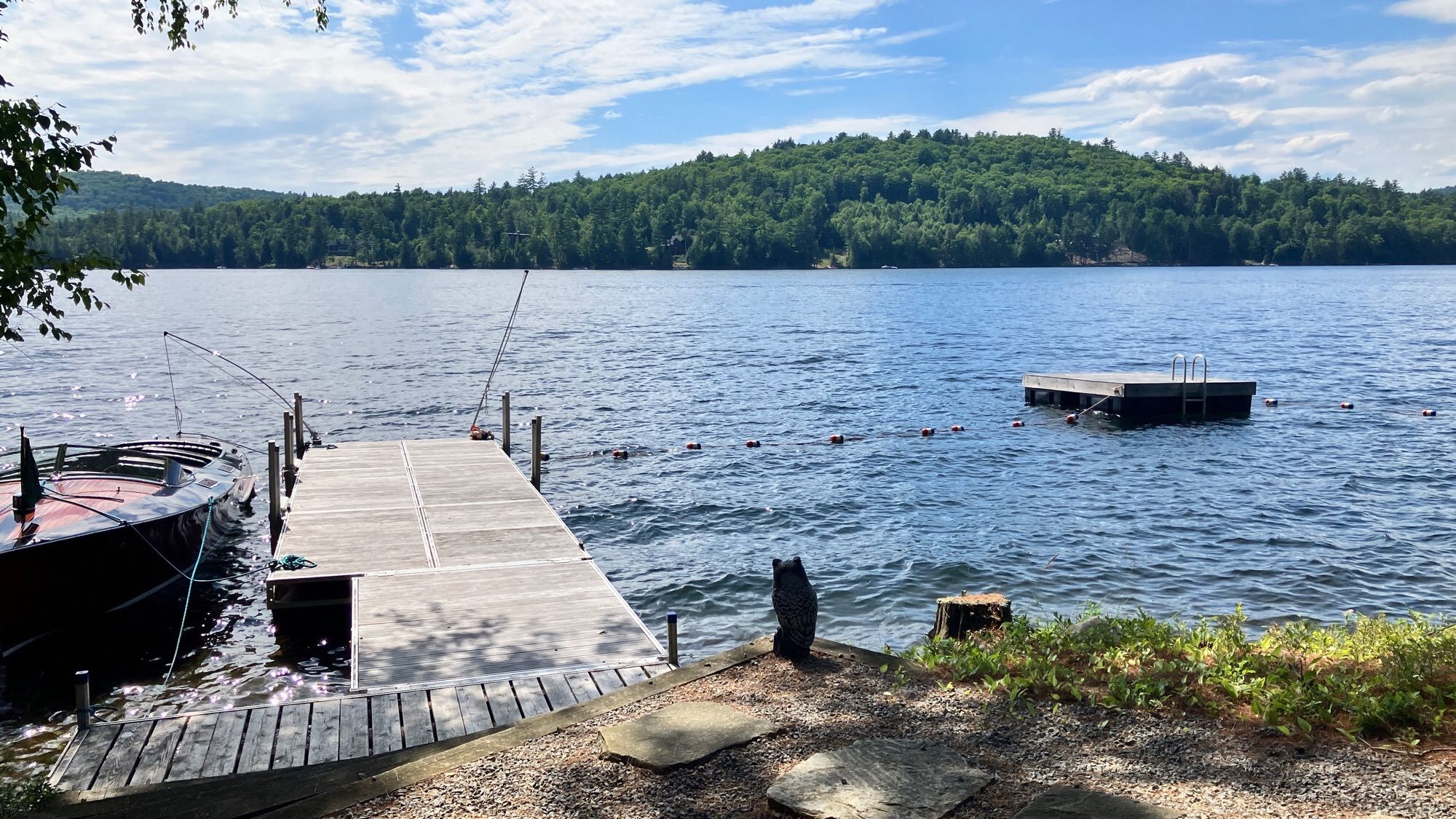 a small lake with a little pier, surrounded by a wooded hilly area