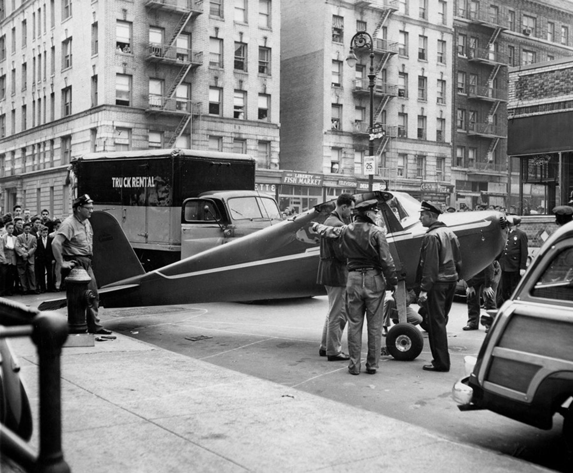 Ein kleines, einmotoriges Flugzeug auf einer Straße in Manhattan. Schwarzweissbild