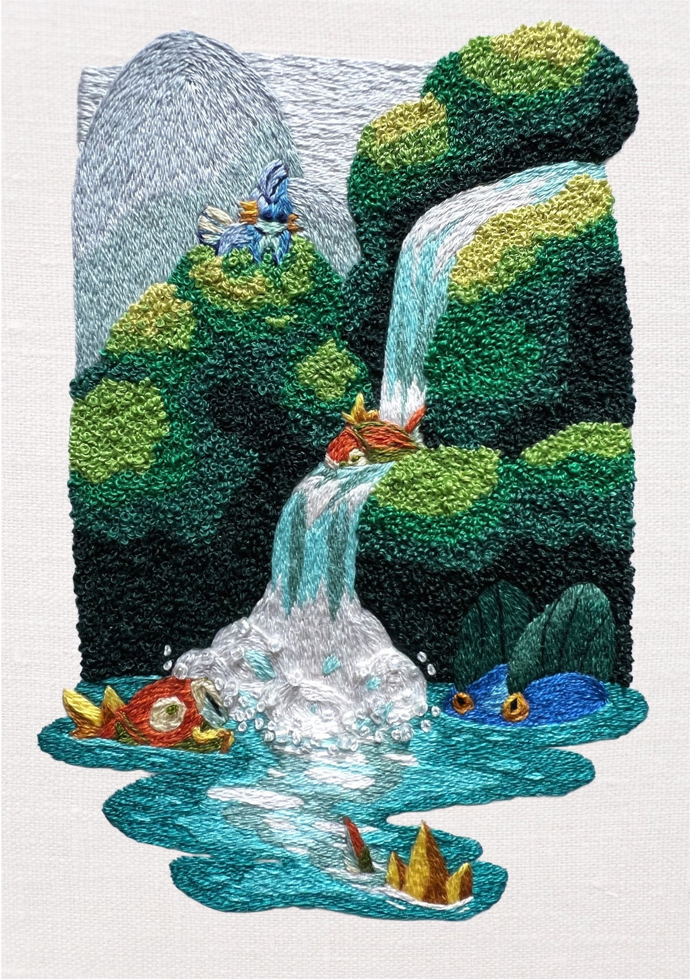 A hand embroidered pokemon fanart of rolling hills and a waterfall with pokemon scattered about. The green hills have a strong texture from the french knots with a mudkip at the top. Several magikarp and a swampert are swimming in the water with one of the magikarp splashing down the waterfall.