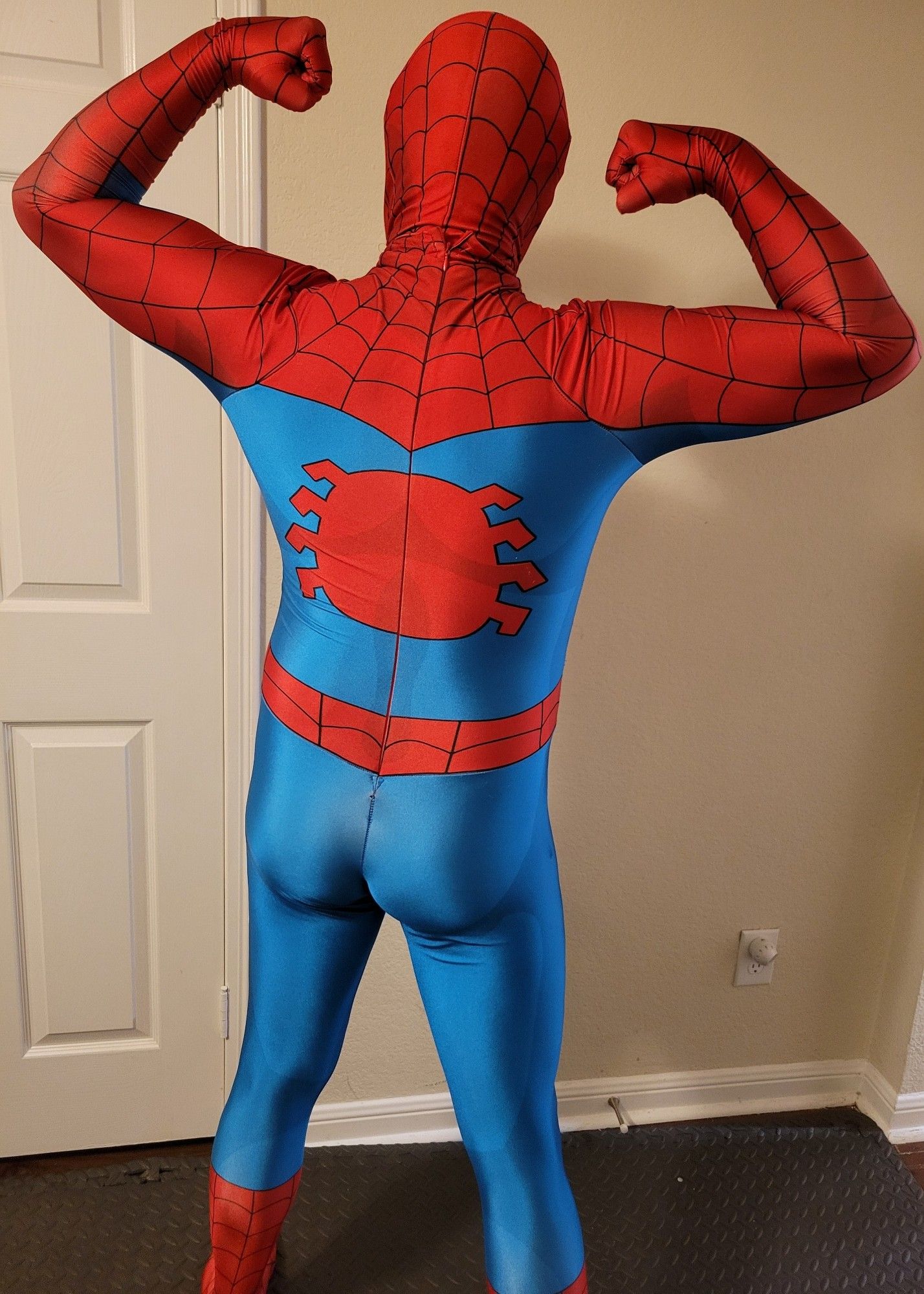 Rear view of man in brightly colored Spider-man costume flexing both arms with a wide stance.