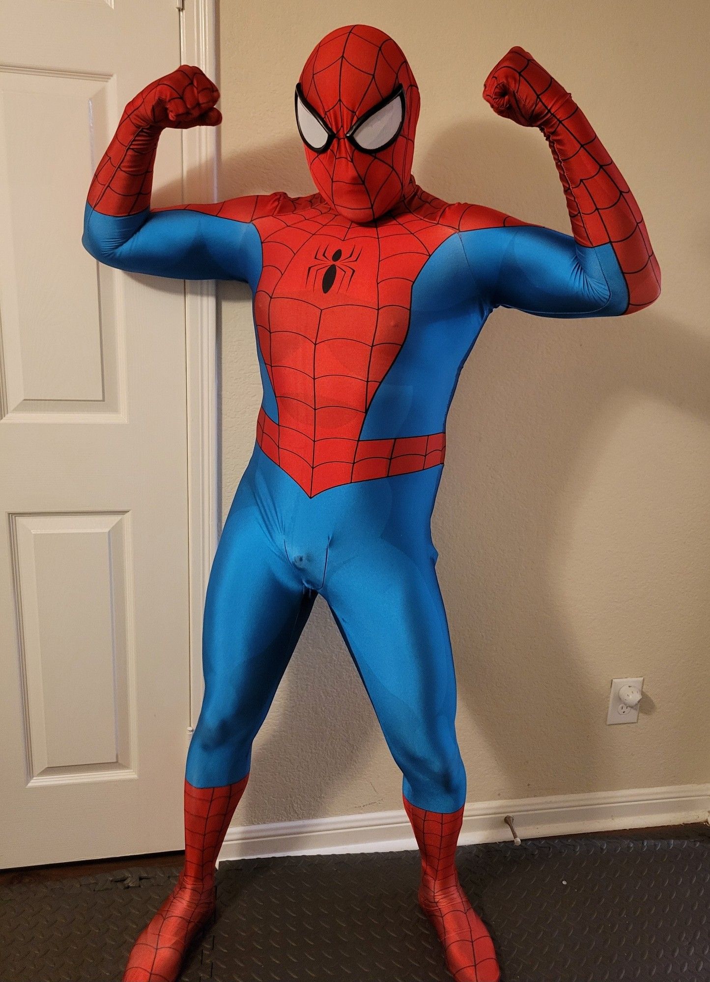 Front view of man in brightly colored Spider-man costume flexing both arms with a wide stance.