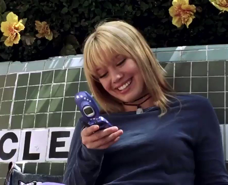 Hillary Duff smiling at a flip phone 