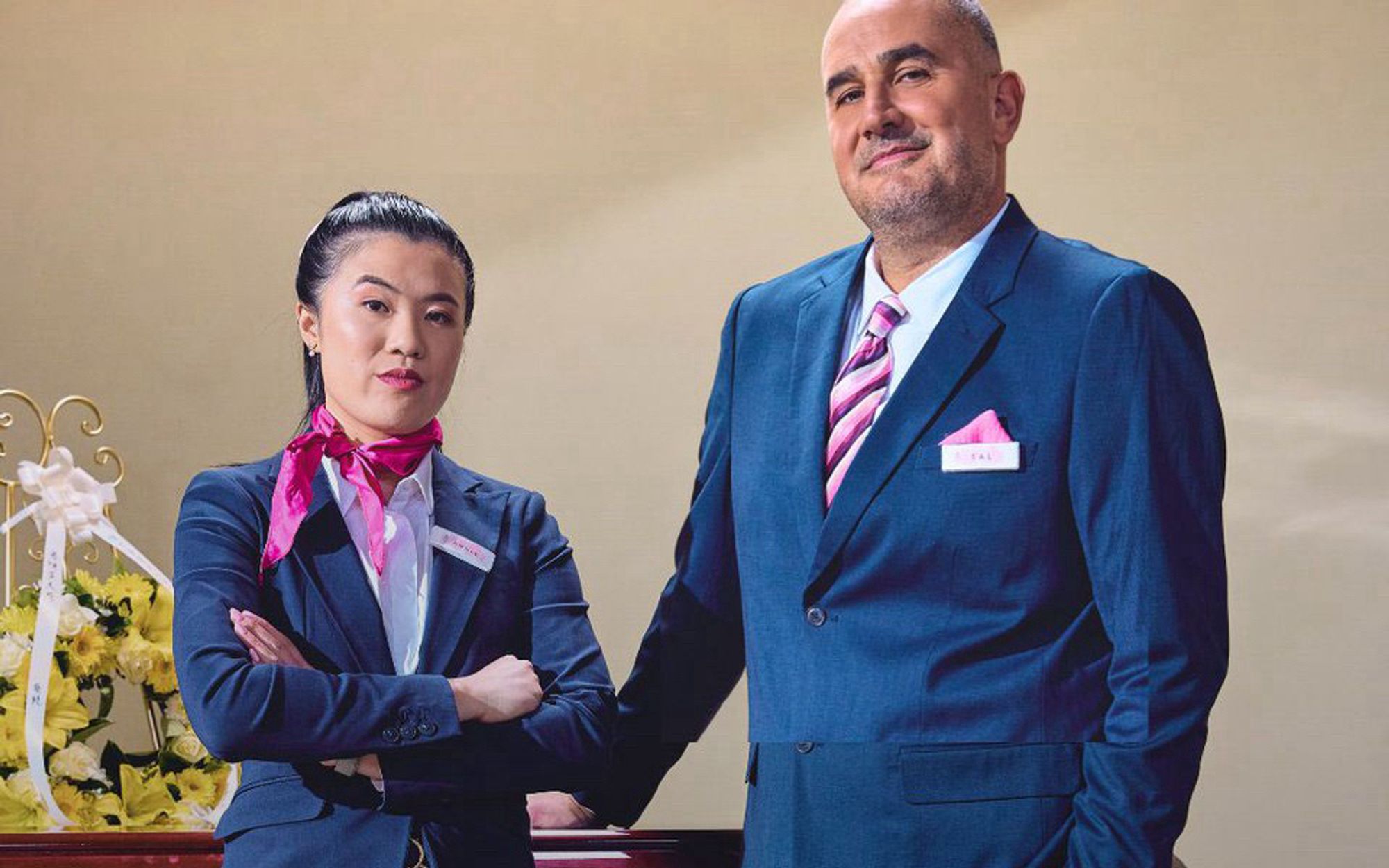 Two funeral directors standing in front of a coffin