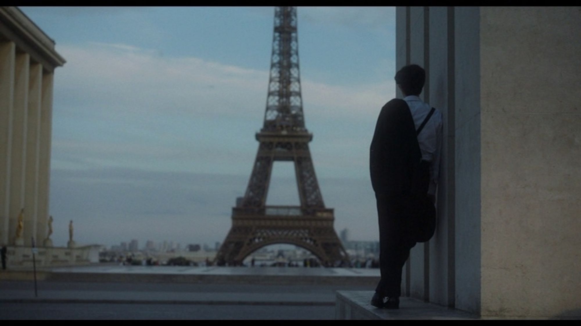 Clara Mastroianni dans le costume de son père au Trocadéro face à la tour Eiffel.