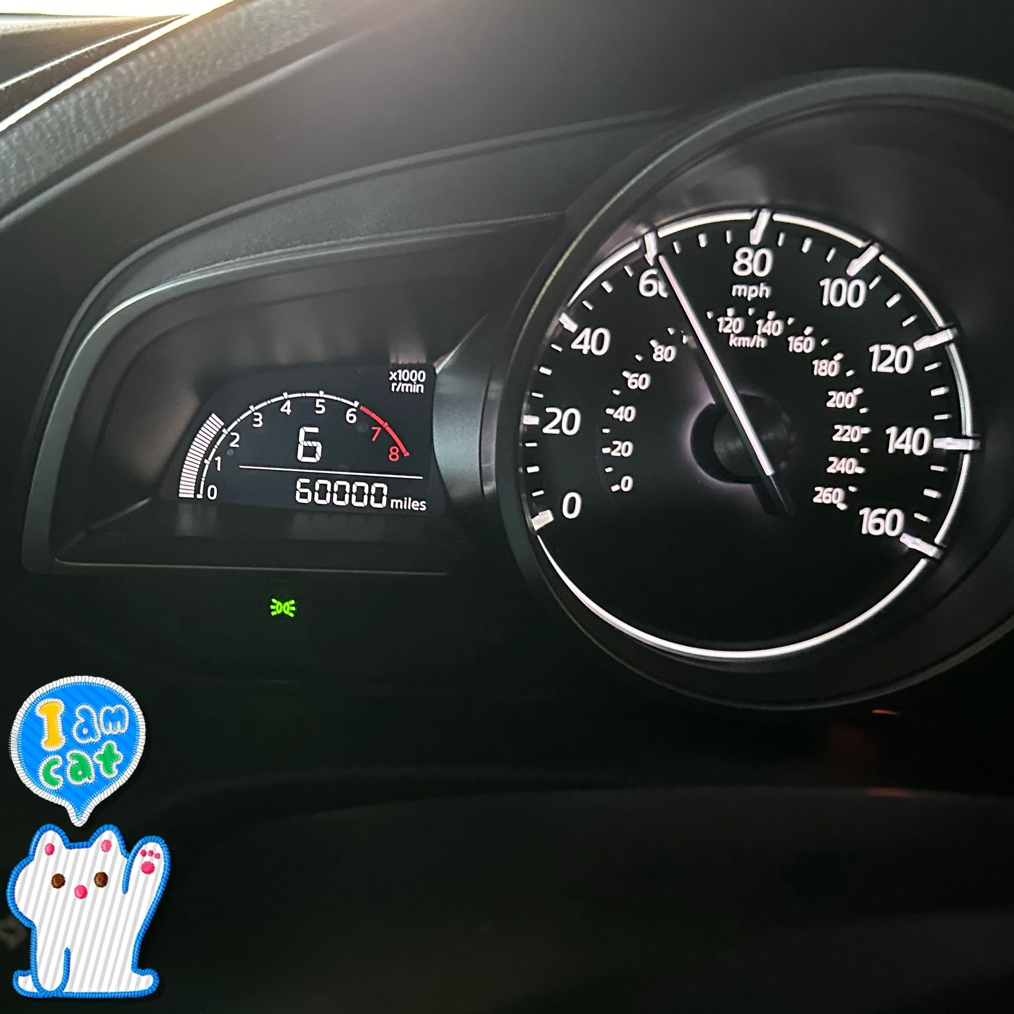 The dashboard of a Mazda3 showing the odometer at 60,000 while traveling at 60 mph and in 6th gear.