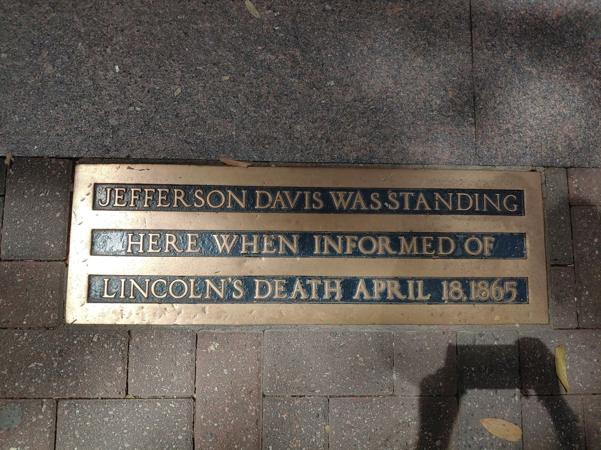 A plaque set into a brick sidewalk declaring, "Jefferson Davis was standing here when informed of Lincoln's death April 18, 1865"