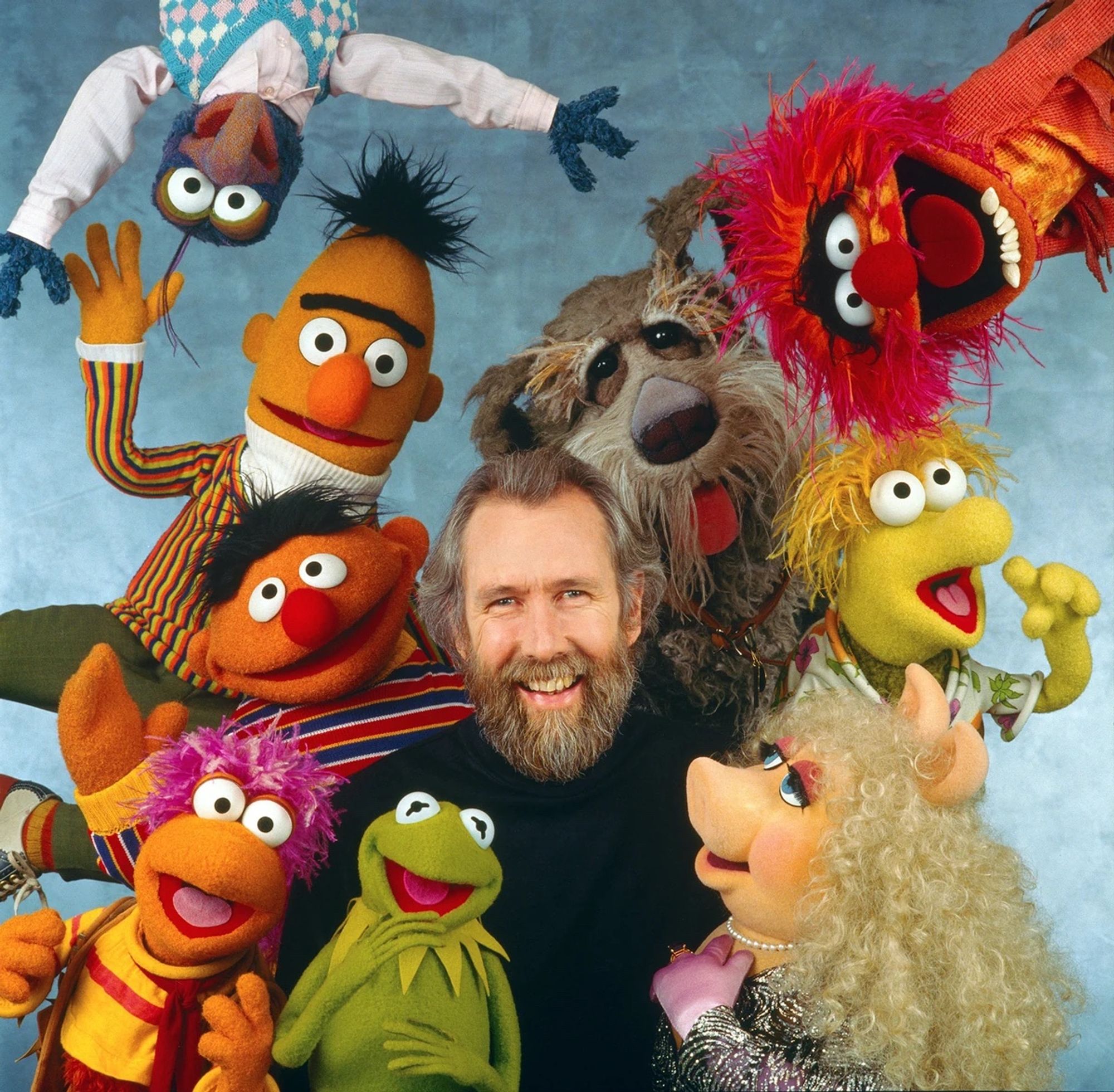 Jim Henson surrounded by Muppets (clockwise from left, top: Gonzo, Animal, Wembley, Miss Piggy, Kermit the Frog, Gobo, Ernie, and Bert)