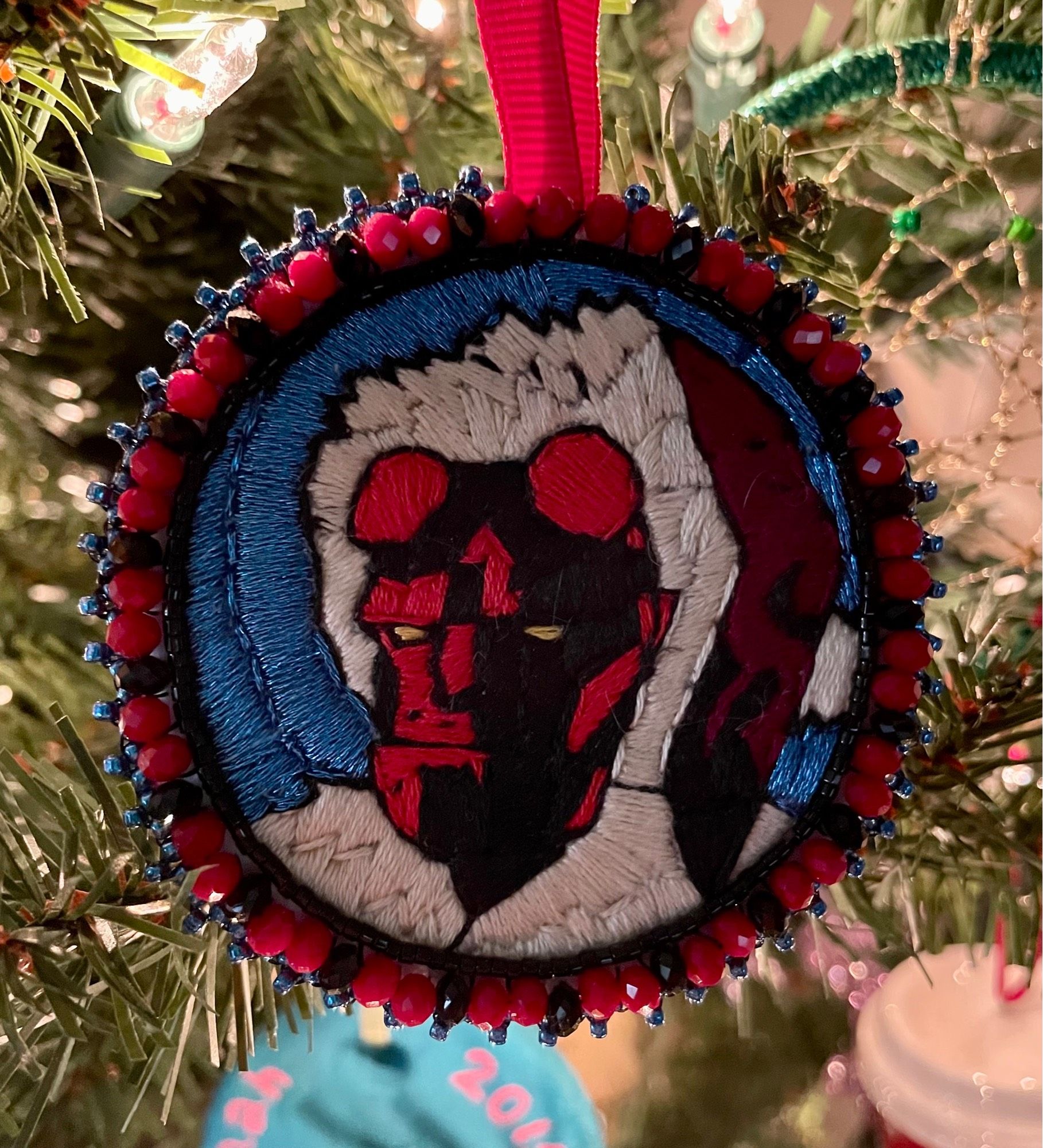 Christmas ornament with embroidered portrait of Hellboy wearing a Santa hat