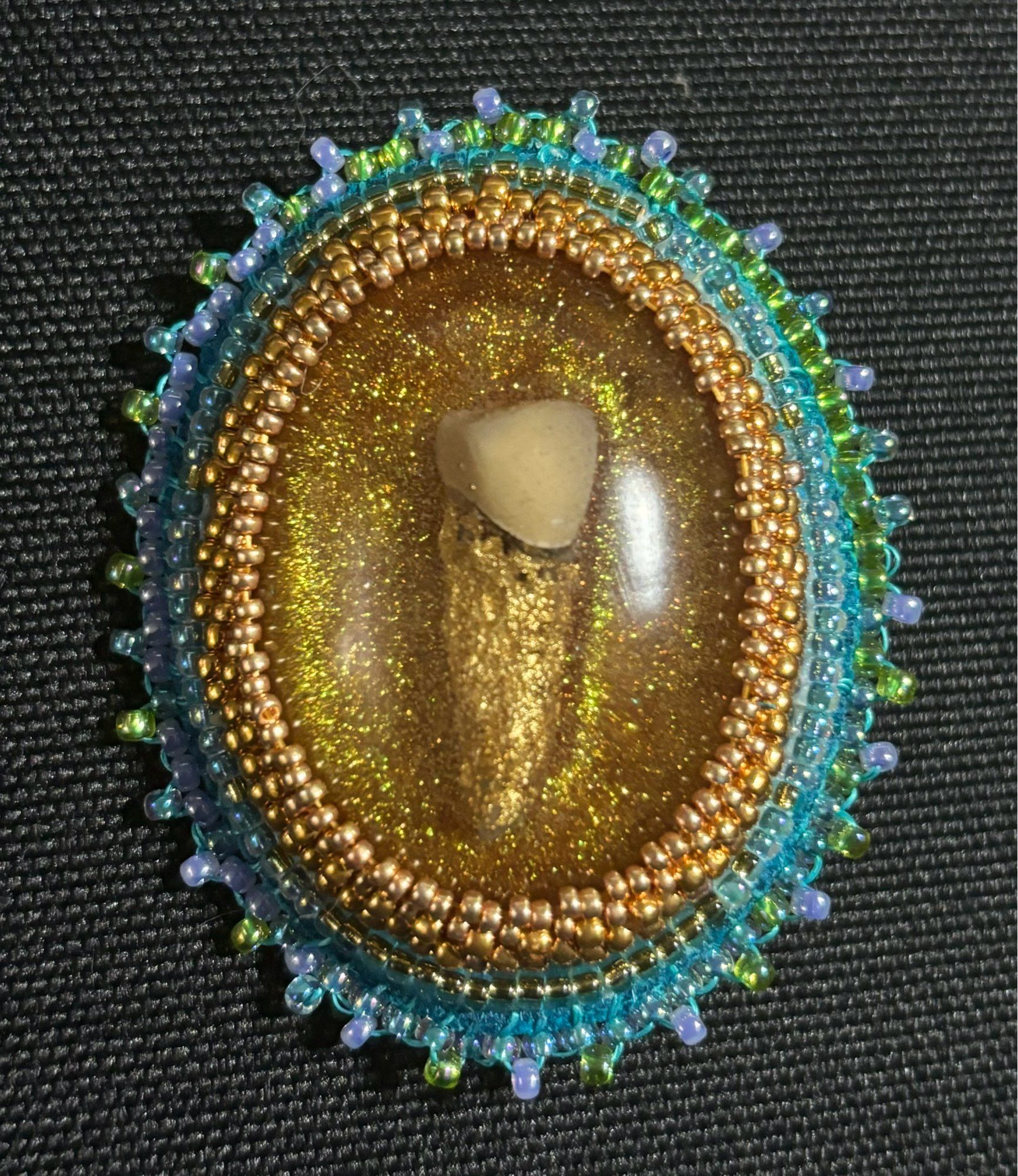 A tooth embedded in resin surrounded by beadwork