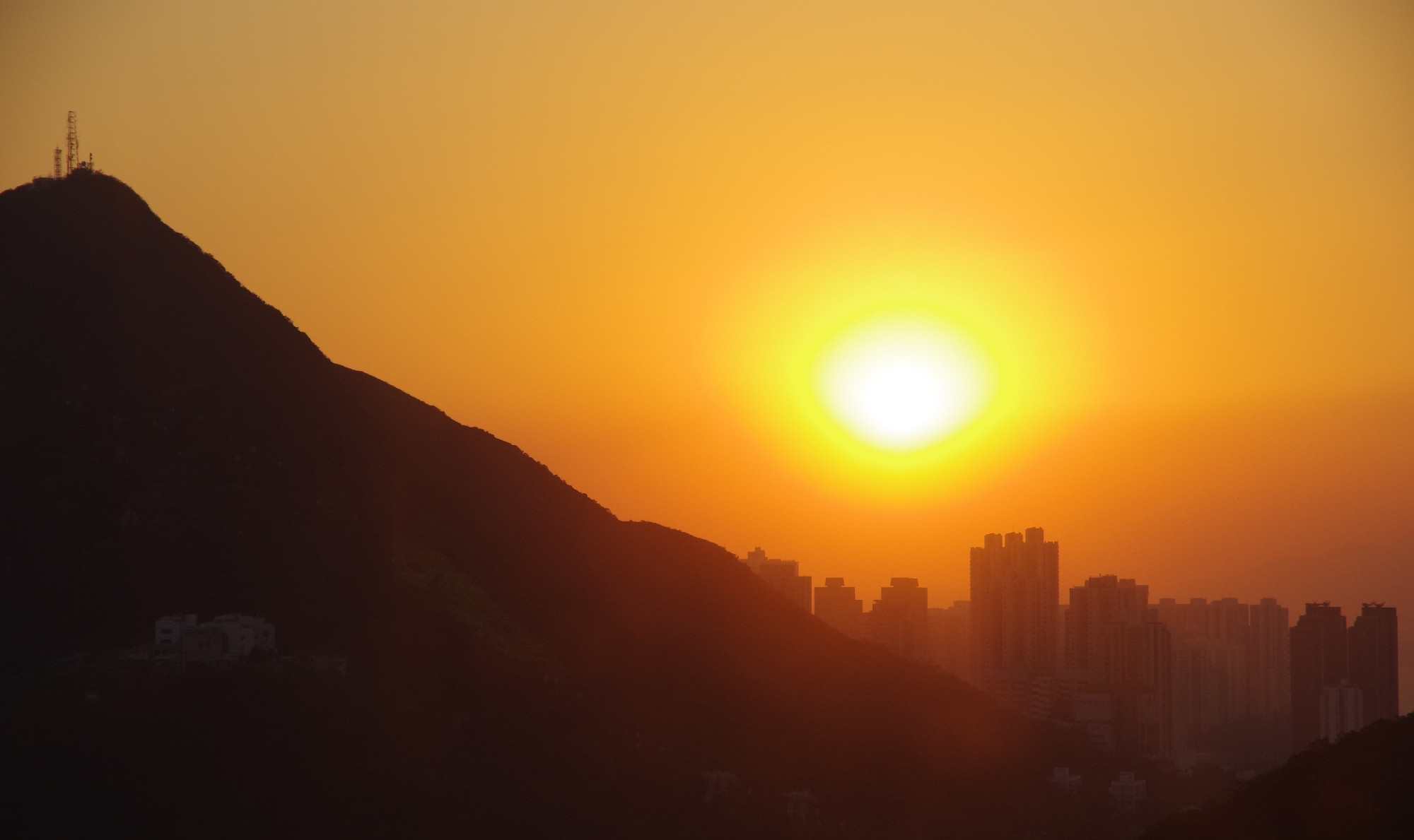 Untergehende sonne vor einem Gebirge und Stadtkulisse 