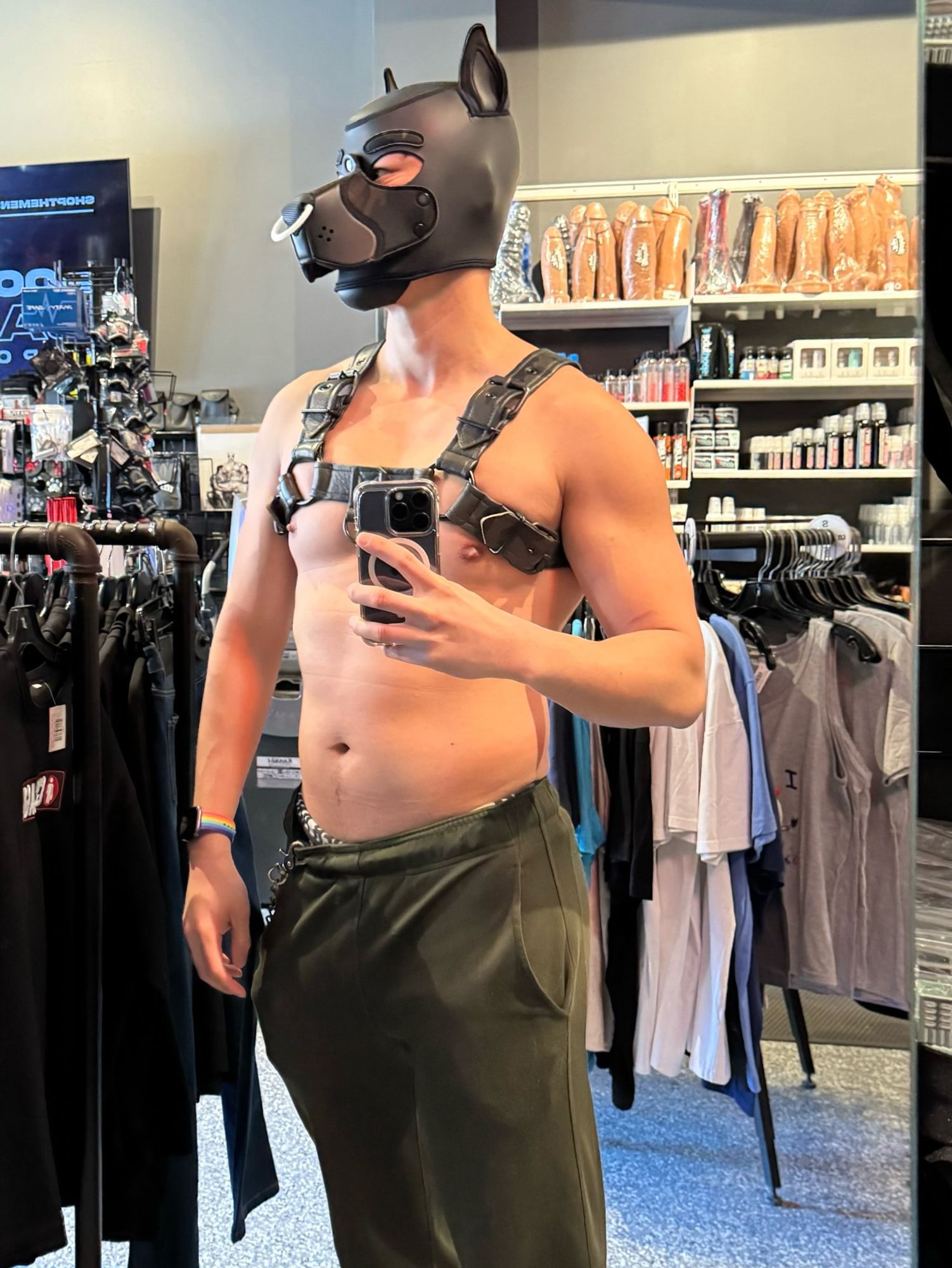 A half naked human dog tries on a leather bull dog harness in green camouflage