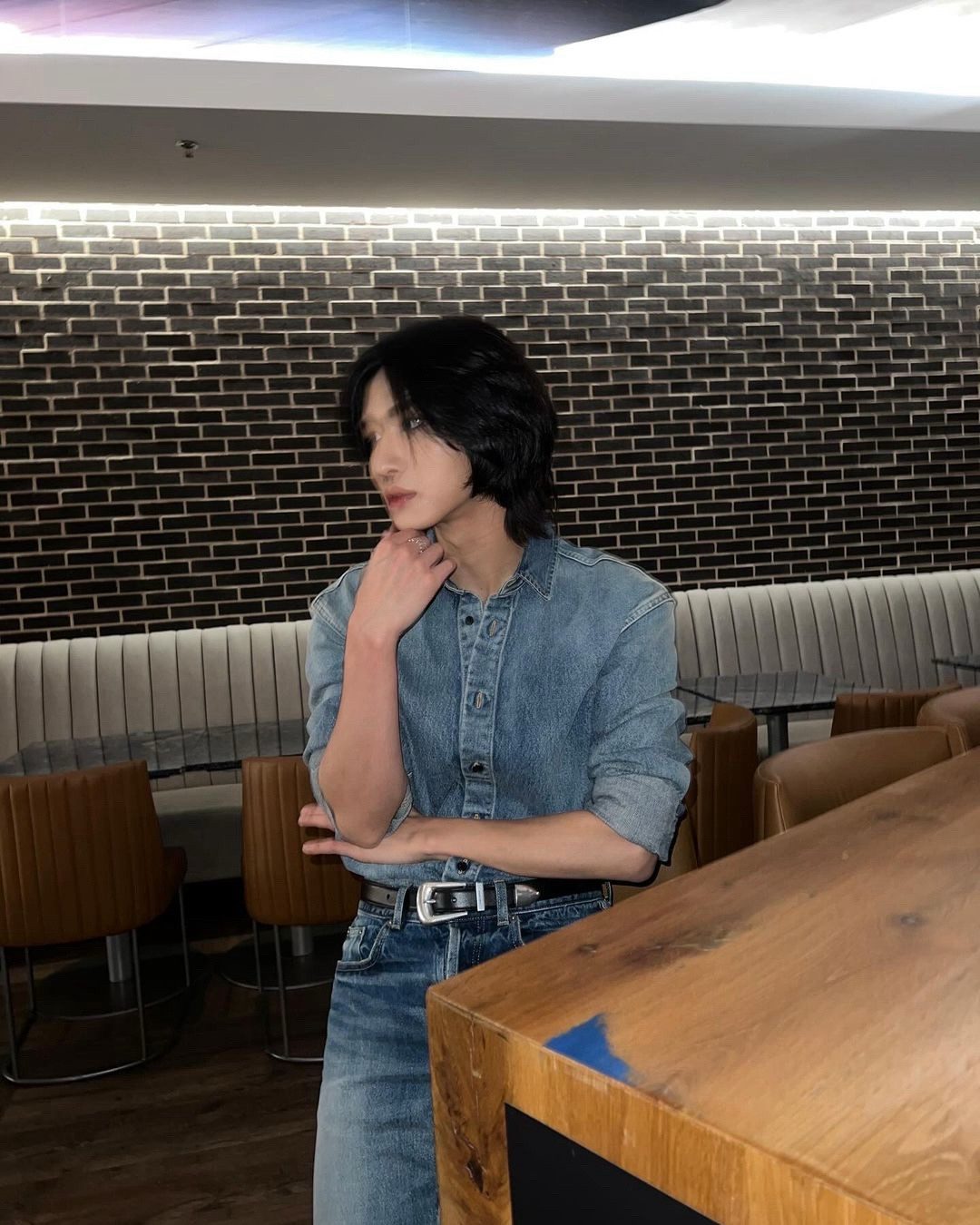 ateez member park seonghwa sitting down, looking to his left in an all denim outfit