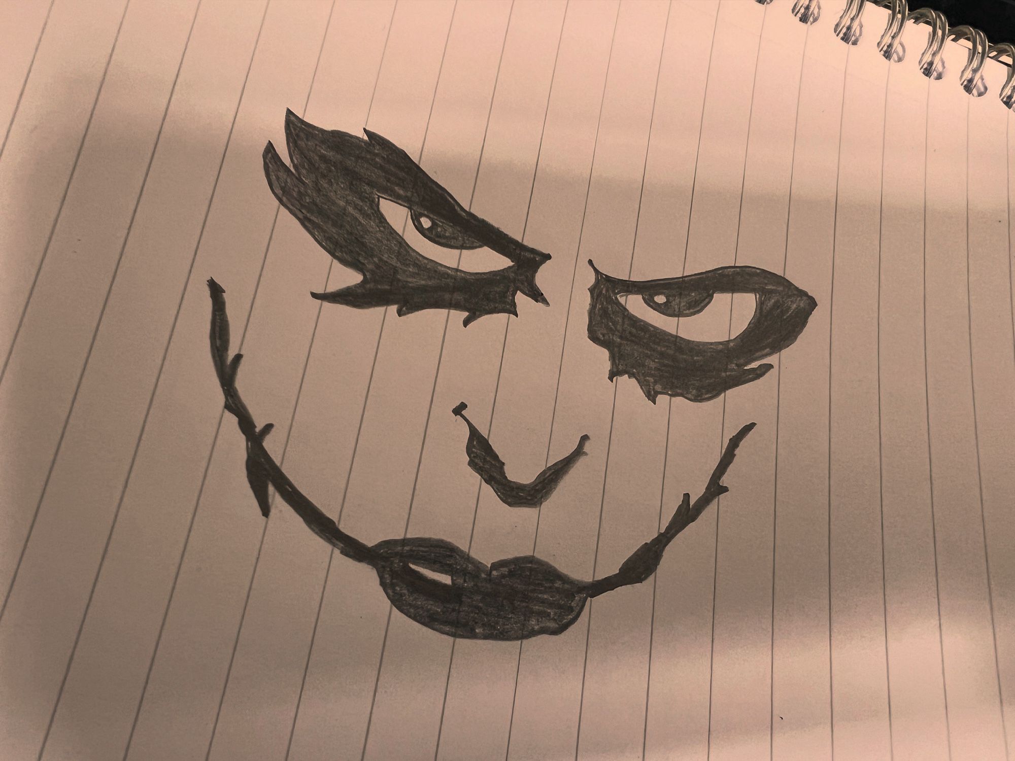 Basic pencil drawing on lined notepad paper of the Joker’s face from Dark Knight, just featuring eyes, nose and scarred mouth.