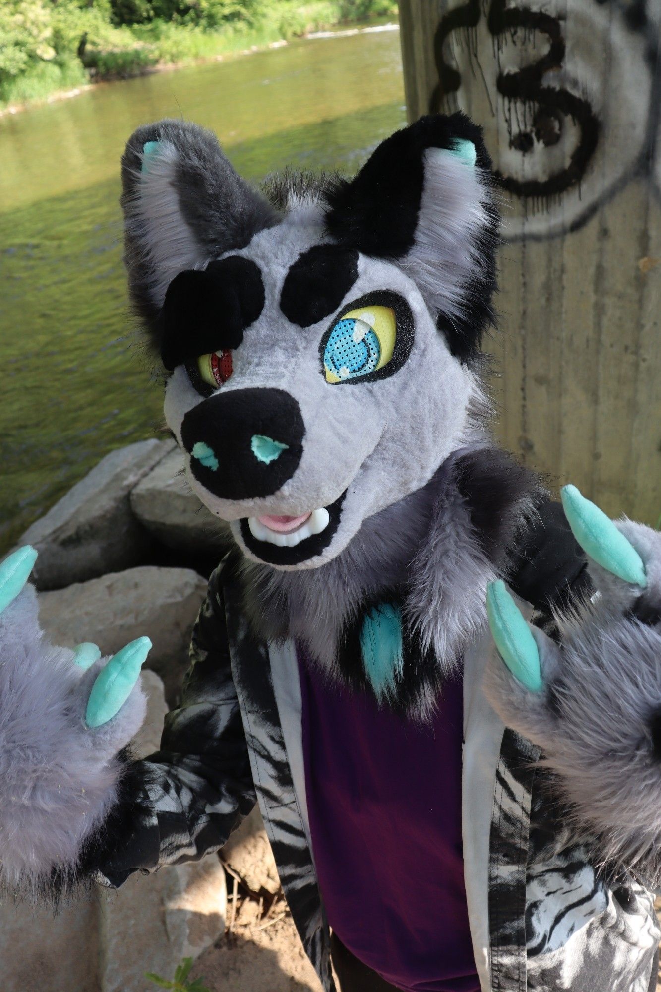 Wolf Fursuit (Blaze) posing underneath a bridge next to a river.