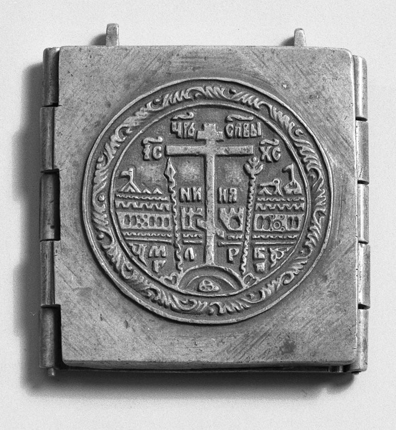 Outer leaf displays Greek Orthodox cross and crucifixion symbols with stylized architectural setting in medallion with rinceau border. Opened, central leaf shows Christ enthroned in attitude of blessing with Gospels, flanked by John the Baptist and the Virgin. Other two leaves contain three saints (right) and St. Michael and two other saints (left). Metal loops at top for suspension. Russian inscriptions on all four decorated panels.

Condition: Fair; faces of figures much rubbed.