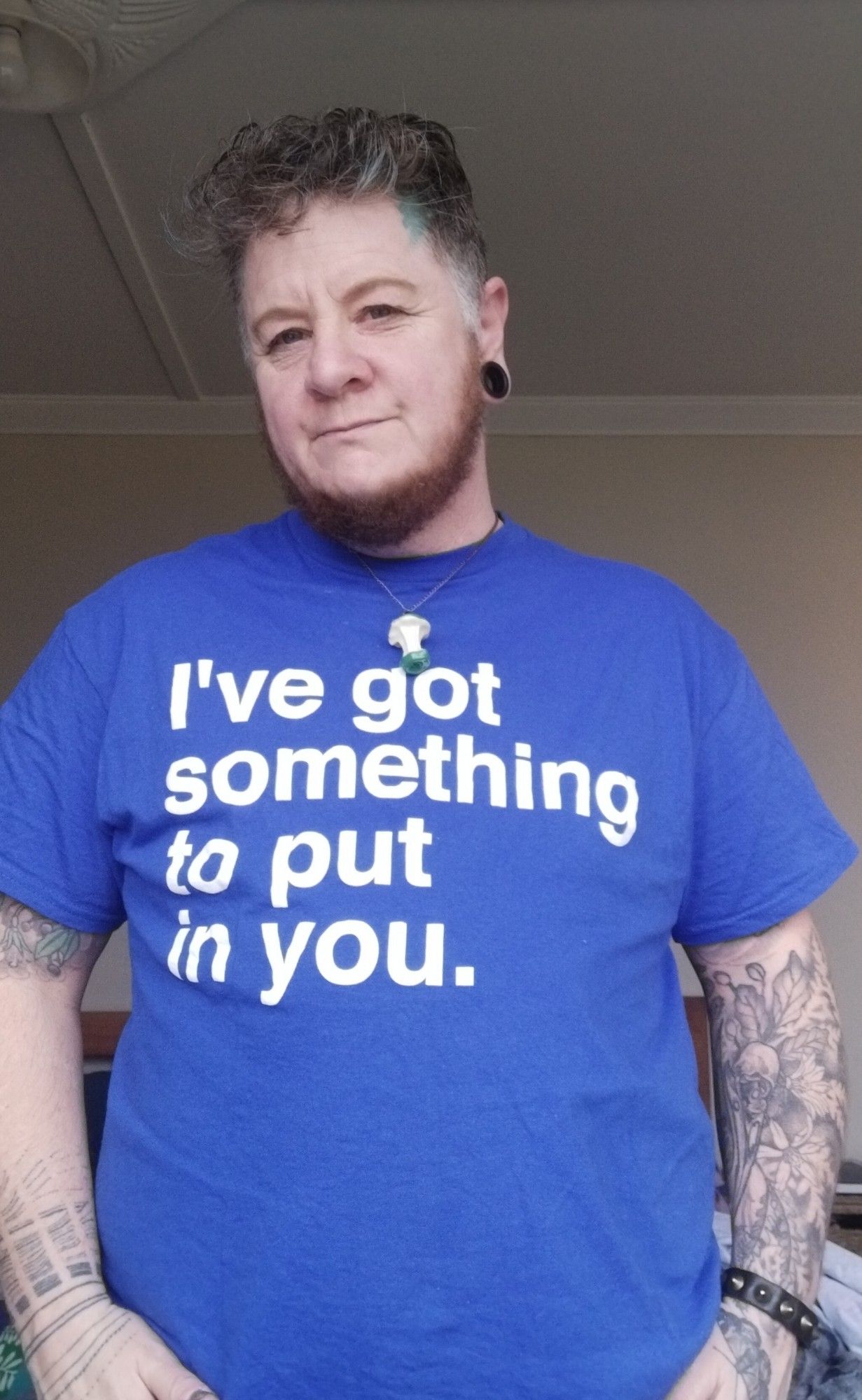 Slightly uncanny leprechaun looking bogan wearing an electric blue t-shirt with the words "I've got something to put in you." In large white letters. Is the font comic sans? I dunno, but it probably should be.